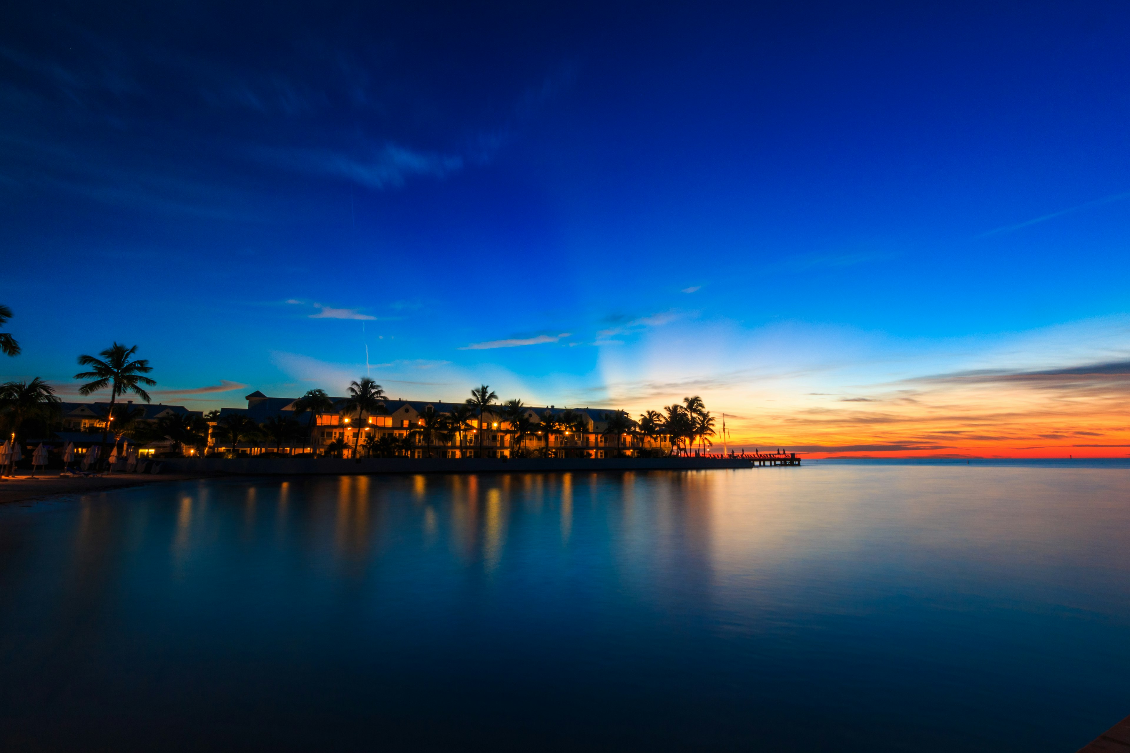 A hotel at the water's edge with lights on in the windows at dusk