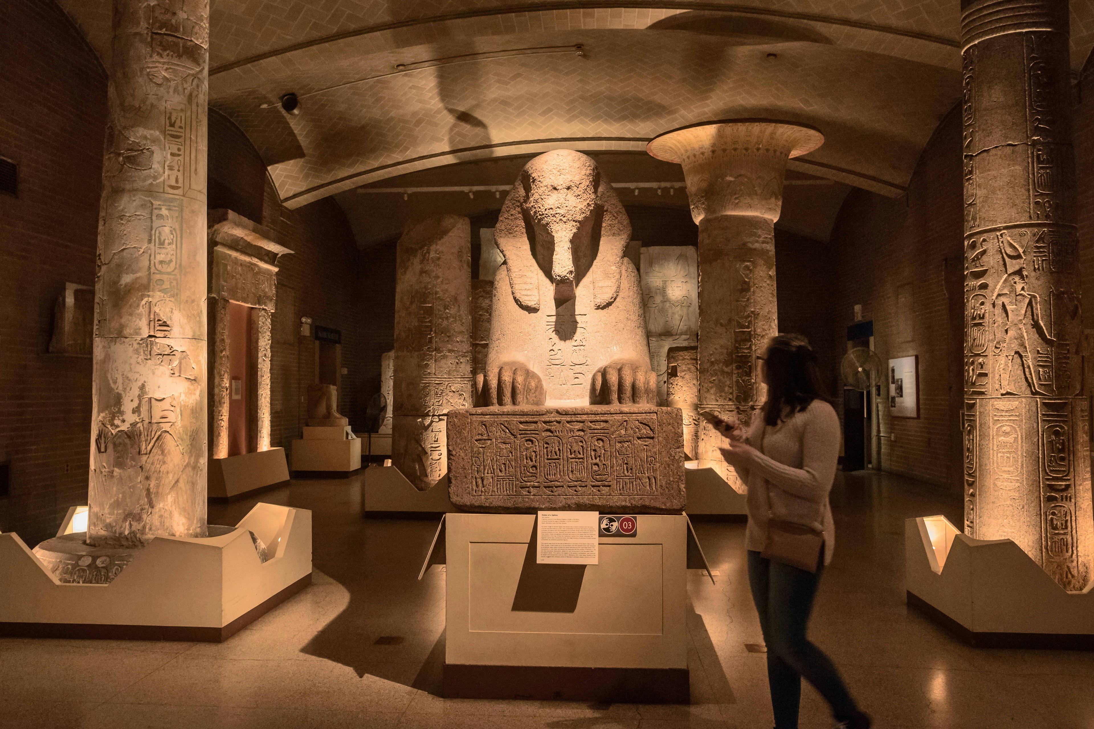 A person walks past the Sphinx of Ramses II in a darkened room in the Penn Museum in Philadelphia