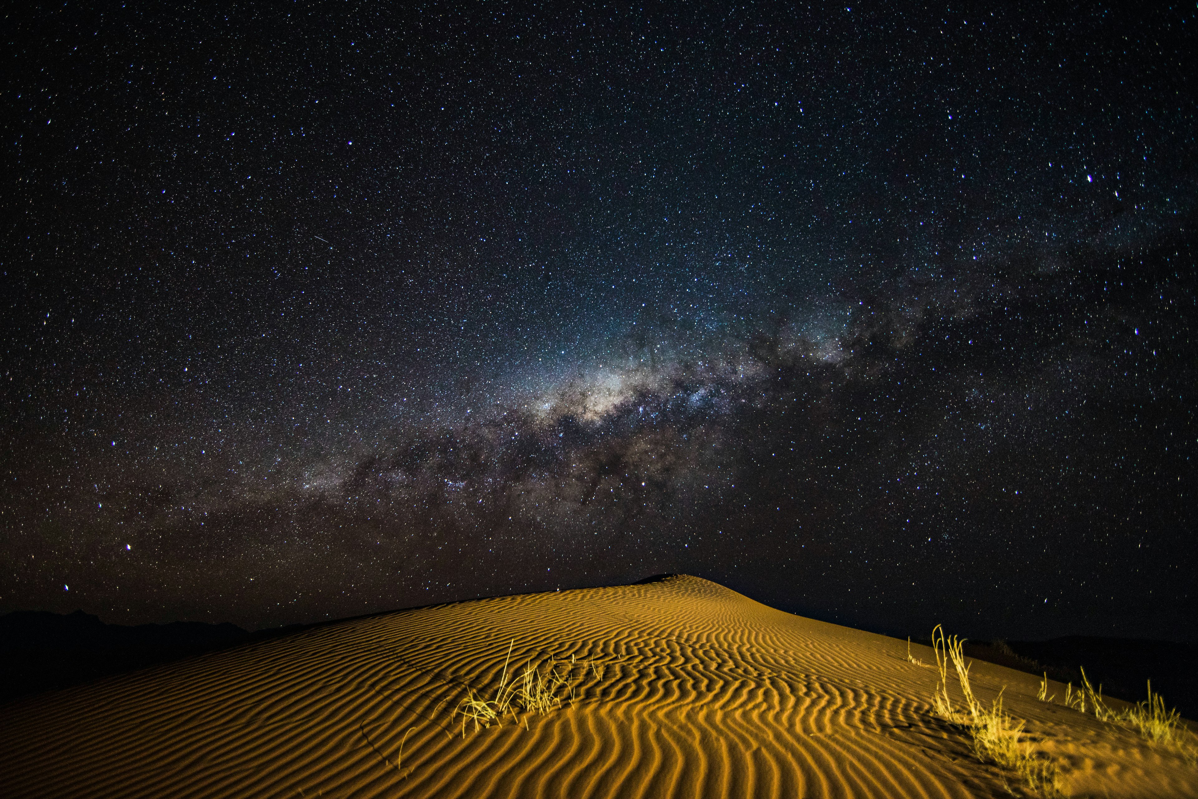 A sand dune at night with stars in the sky above