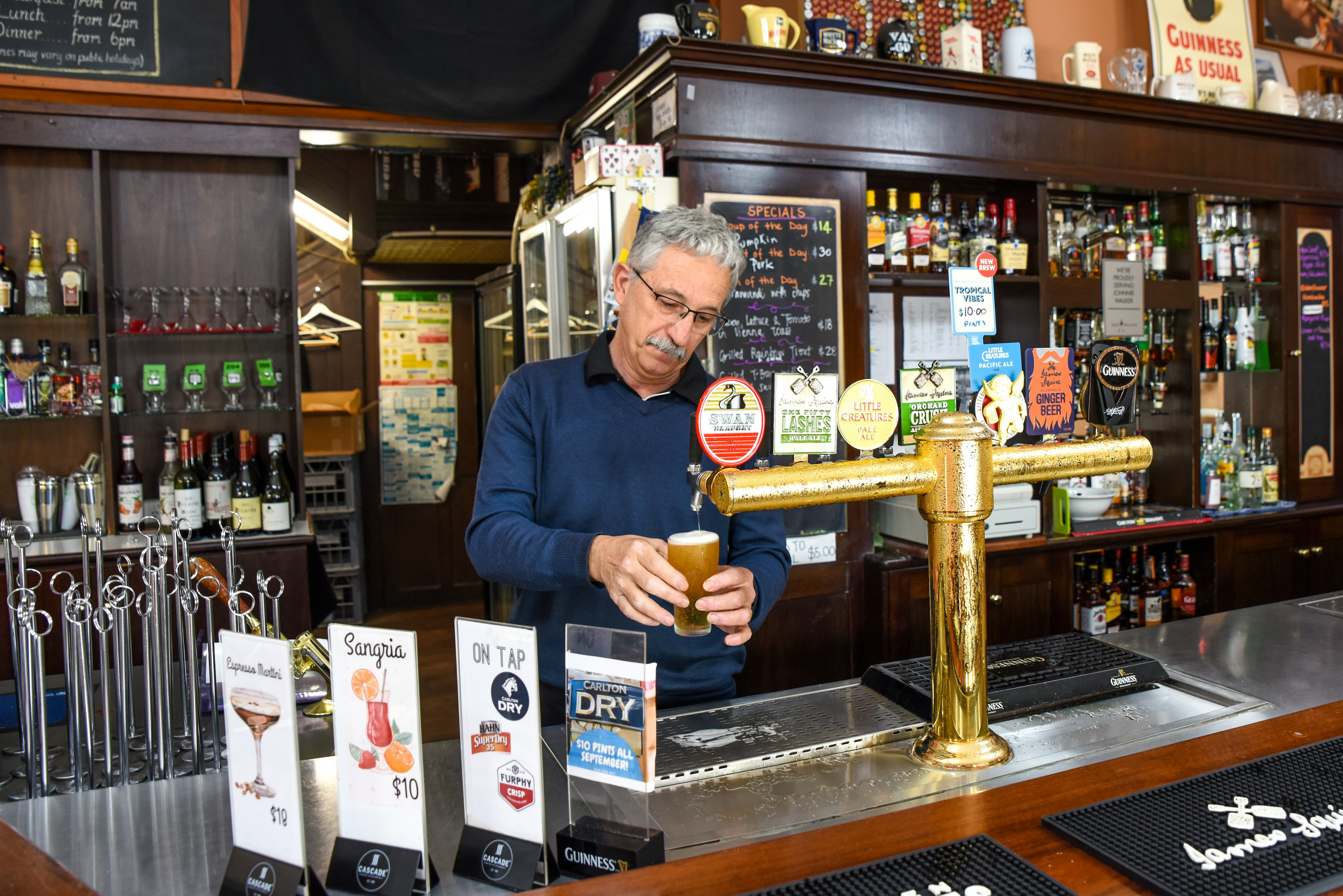 Man pouring a beer behind a pub bar in Australia