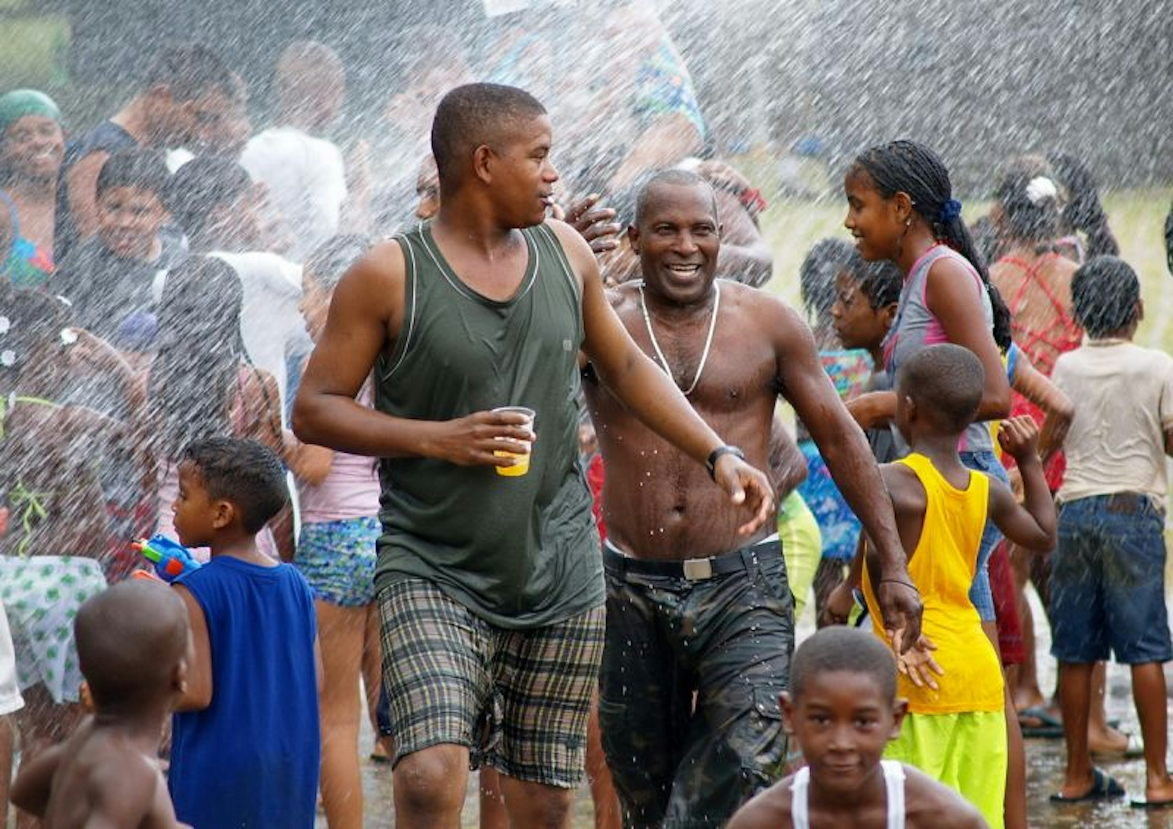 A crowd of people being sprayed with water at a street festival