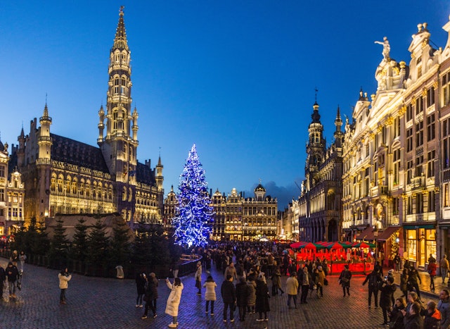 A lit Christmas tree stands in a busy city square