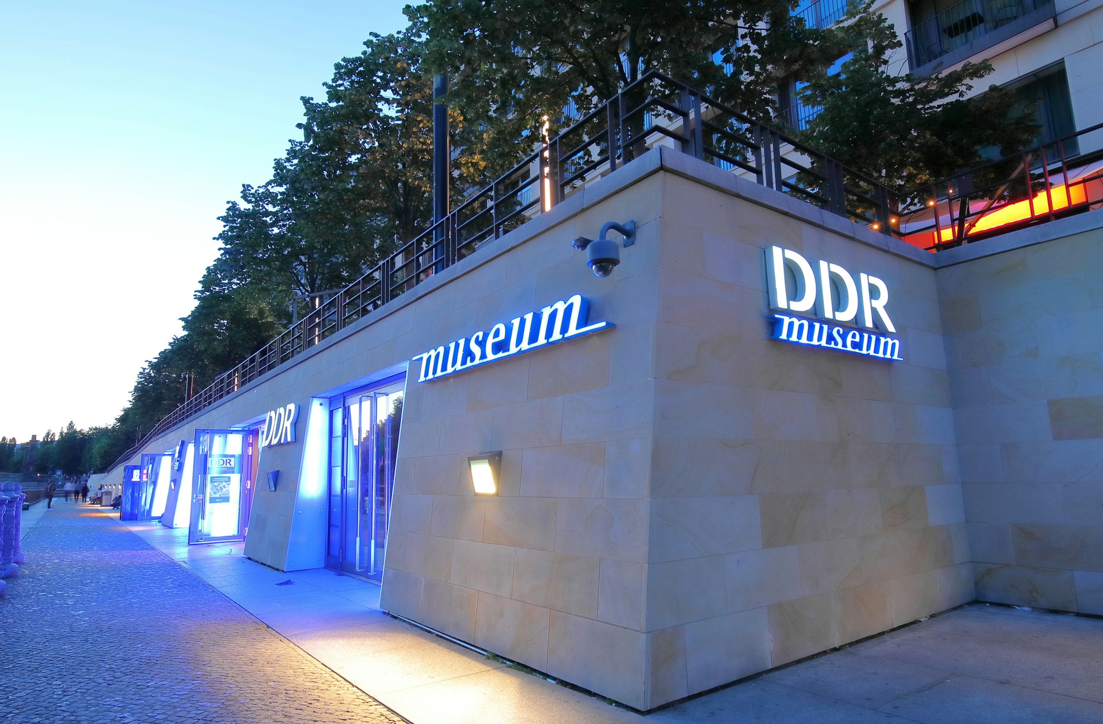 The exterior of the DDR Museum in Berlin, lit up with blue lights at night