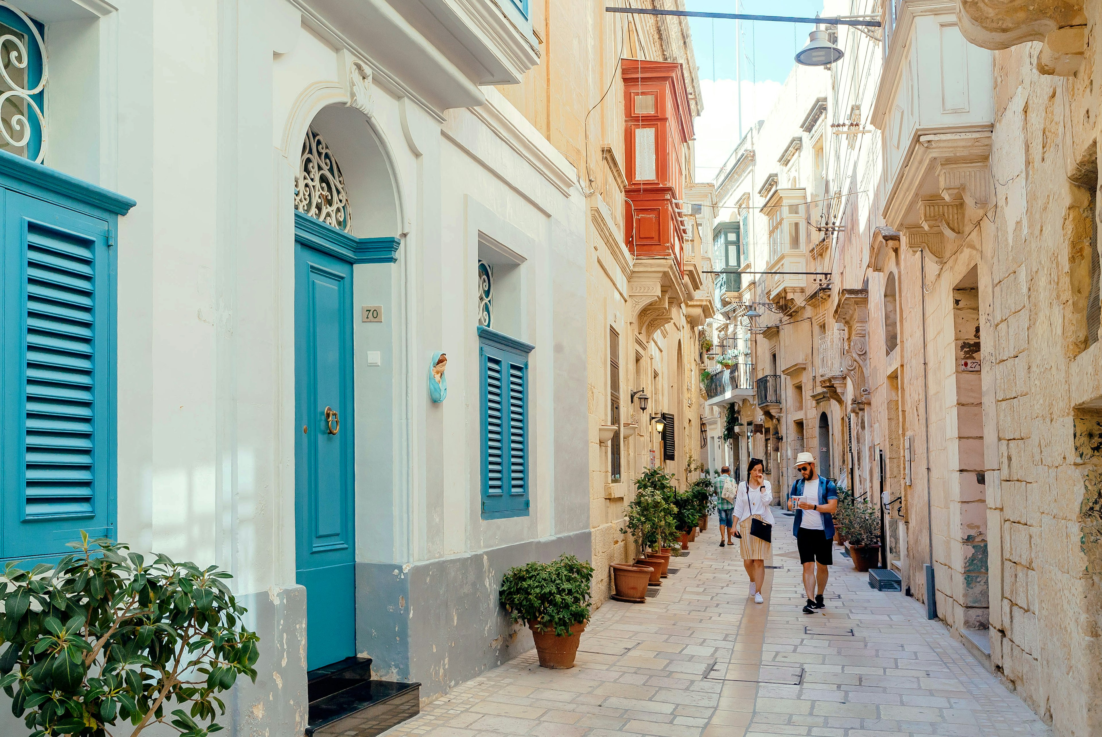 Tourists walking down narrow streets with wooden doors and historical houses