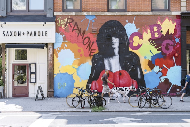 A man walks his dog in front of street art at the corner of Bleecker and Bowery.