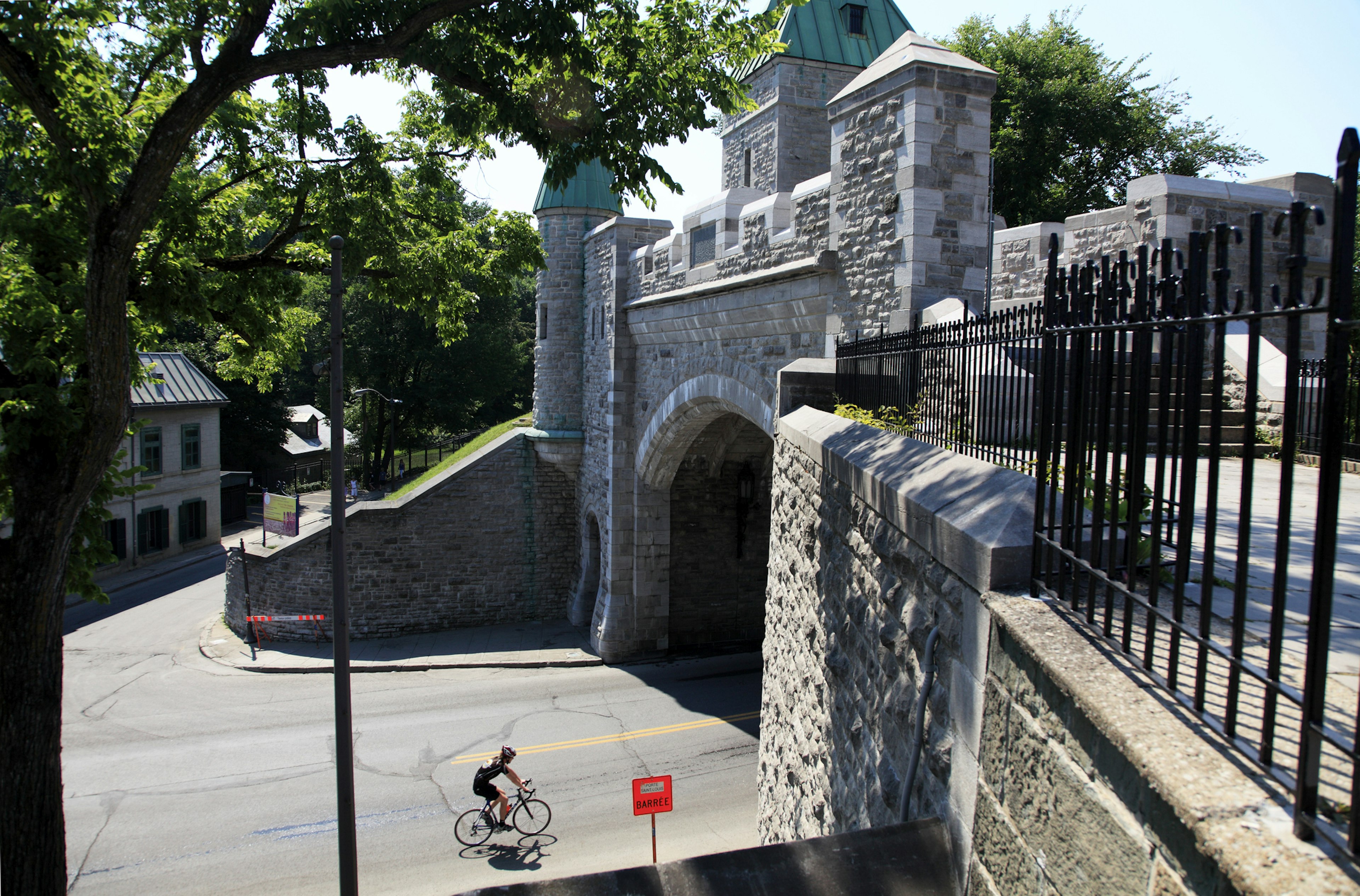 A lone cyclist about to pass through the Porte Saint-Louis in the Old Town, ϳé City, ϳé, Canada