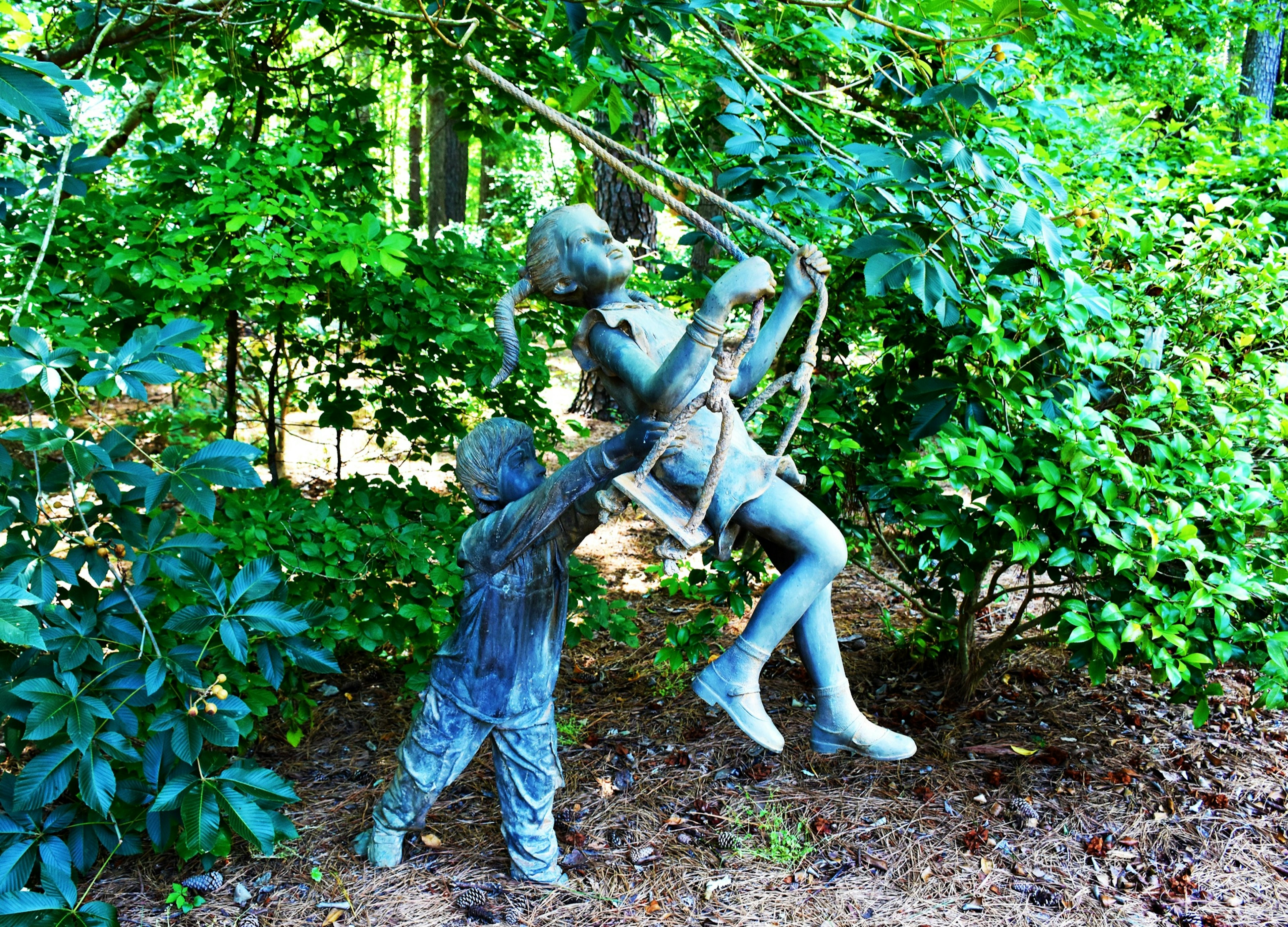 Statue of a young boy pushing a young girl on a swing at the Cape Fear Botanical Garden in Fayetteville, North Carolina.