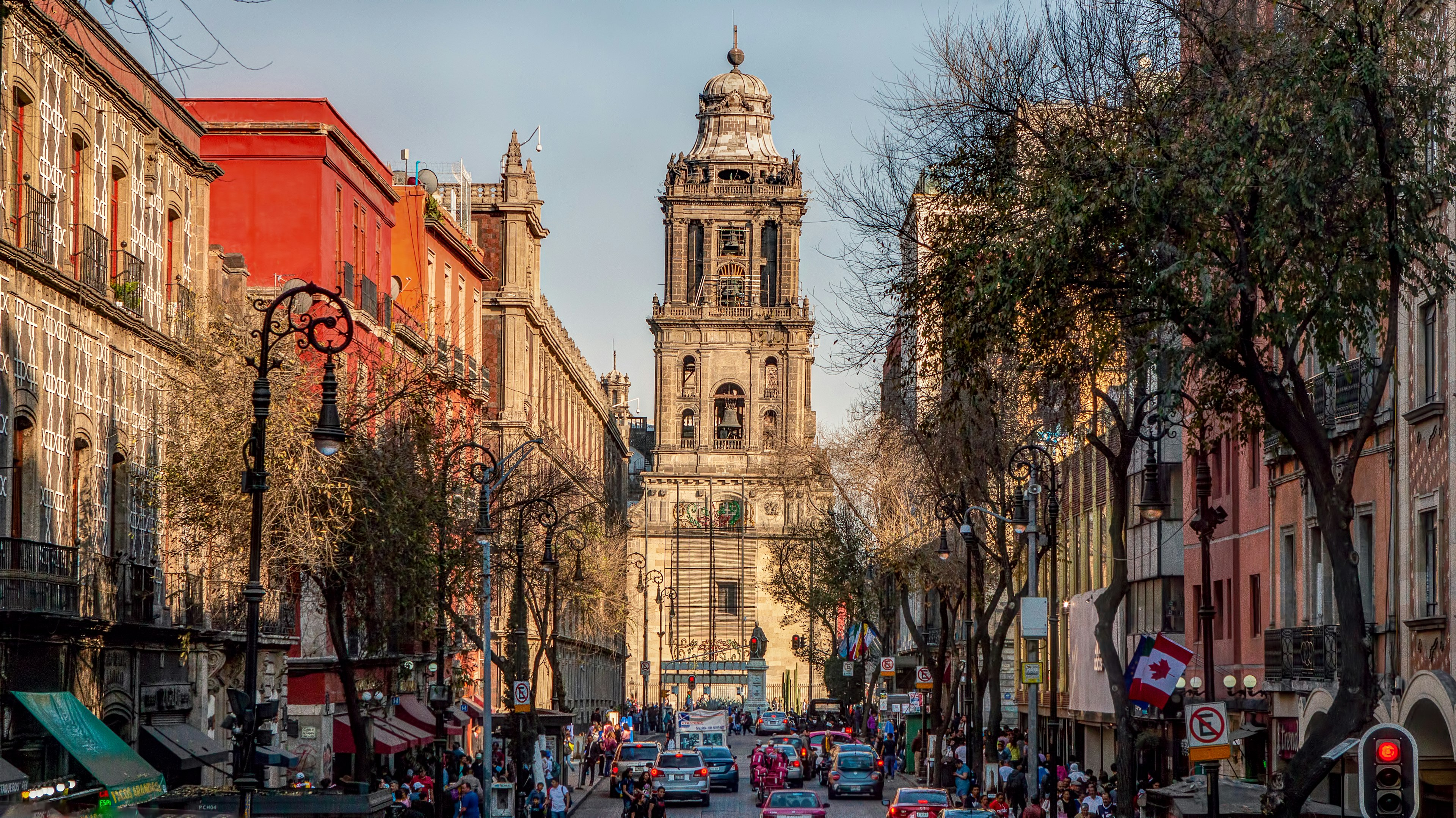 A busy street filled with cars and people leads toward the ó and the Metropolitan Cathedral in Mexico City, Mexico