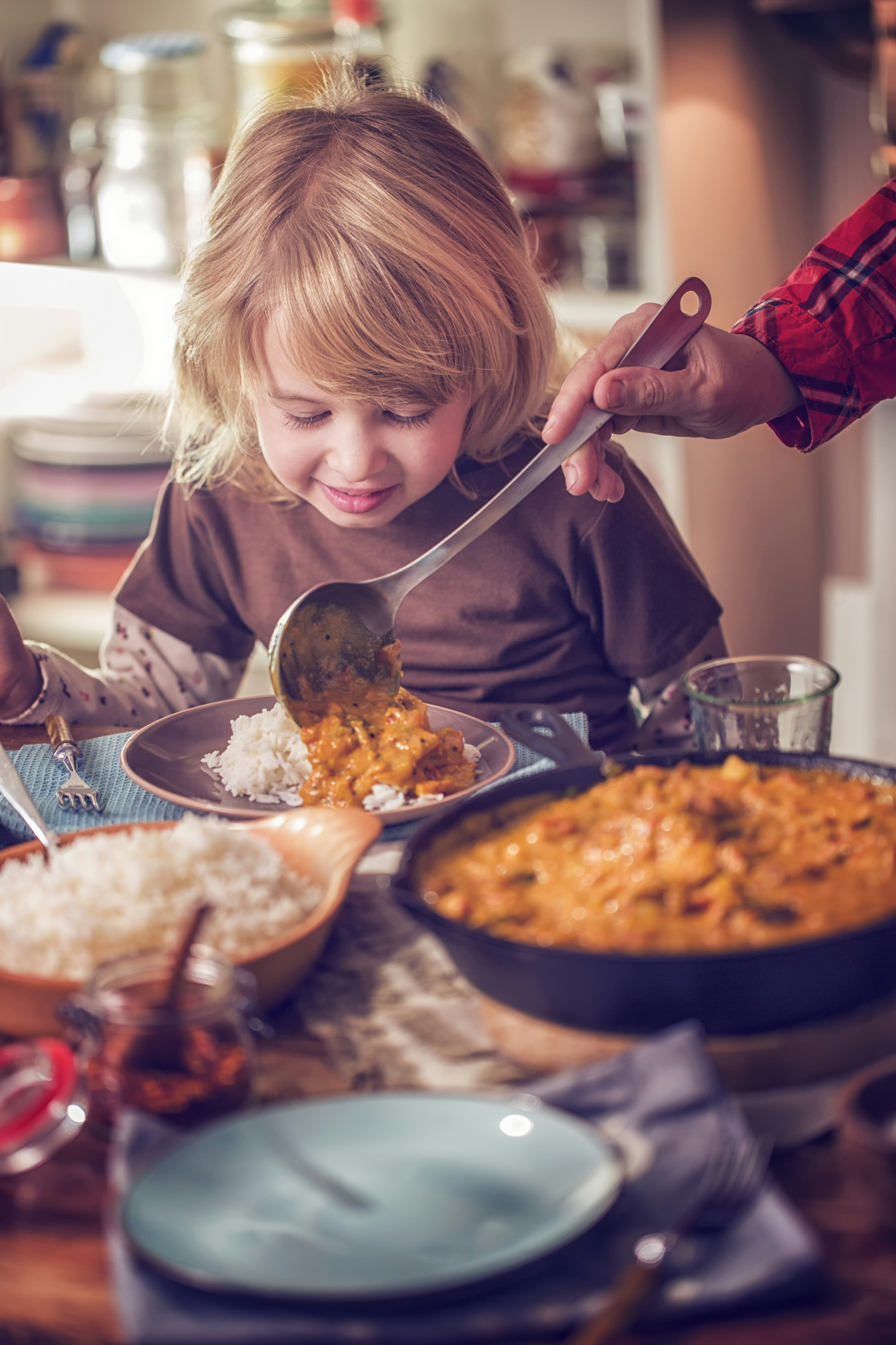 Young family eating homemade chicken curry dish with basmati rice