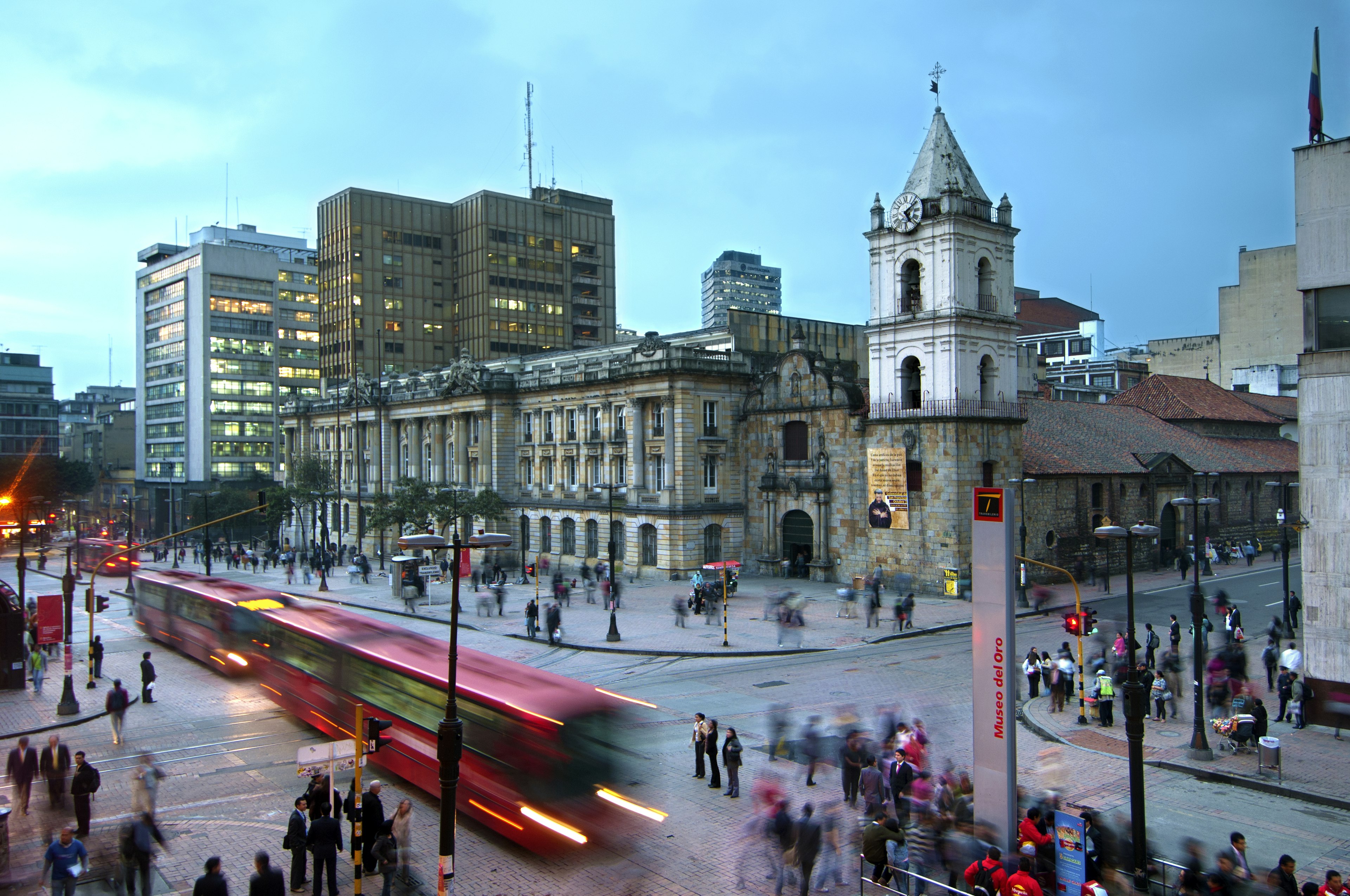 A red TransMilenio bus stops near the Iglesia de San Francisco, Bogota, Colombia