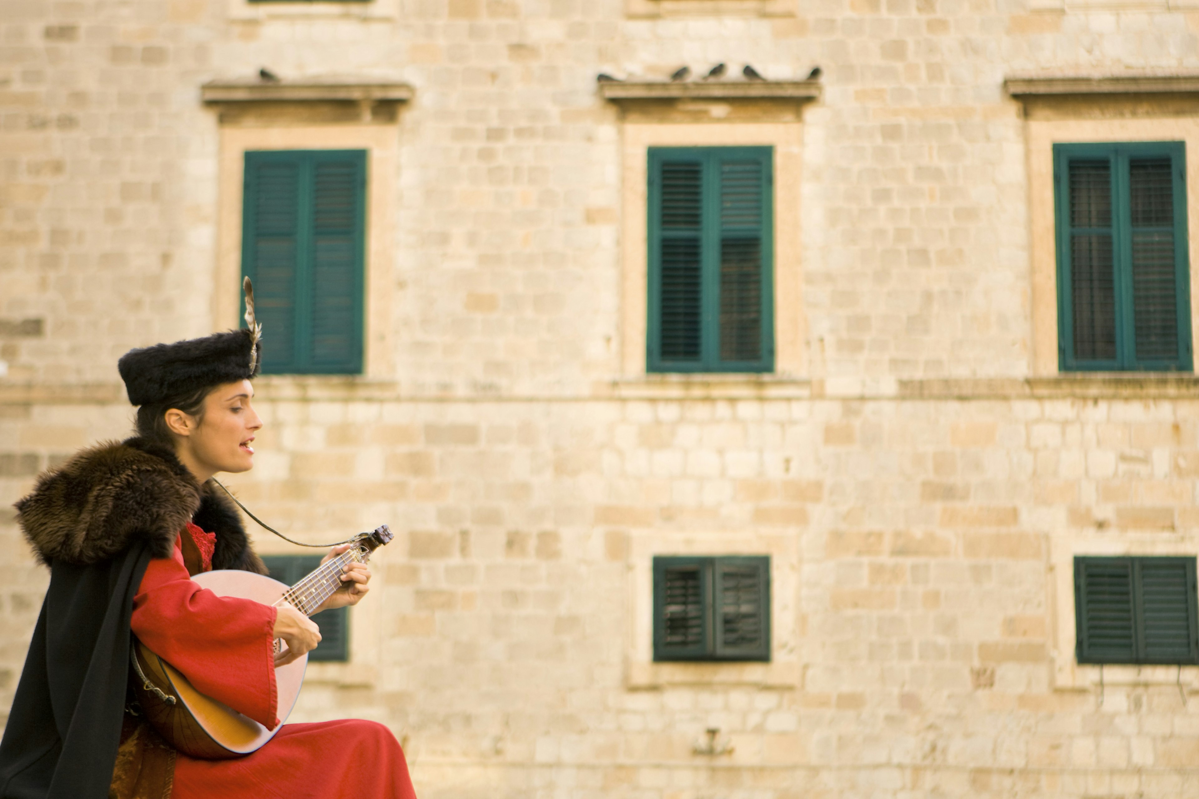 MR woman dressed in medieval costume performing in front of Church of St. Blaise located at the Luza near the Placa (Stradun) in Stari Grad (Old Town) Dubrovnik, Croatia.  A UNESCO World Heritage Site.