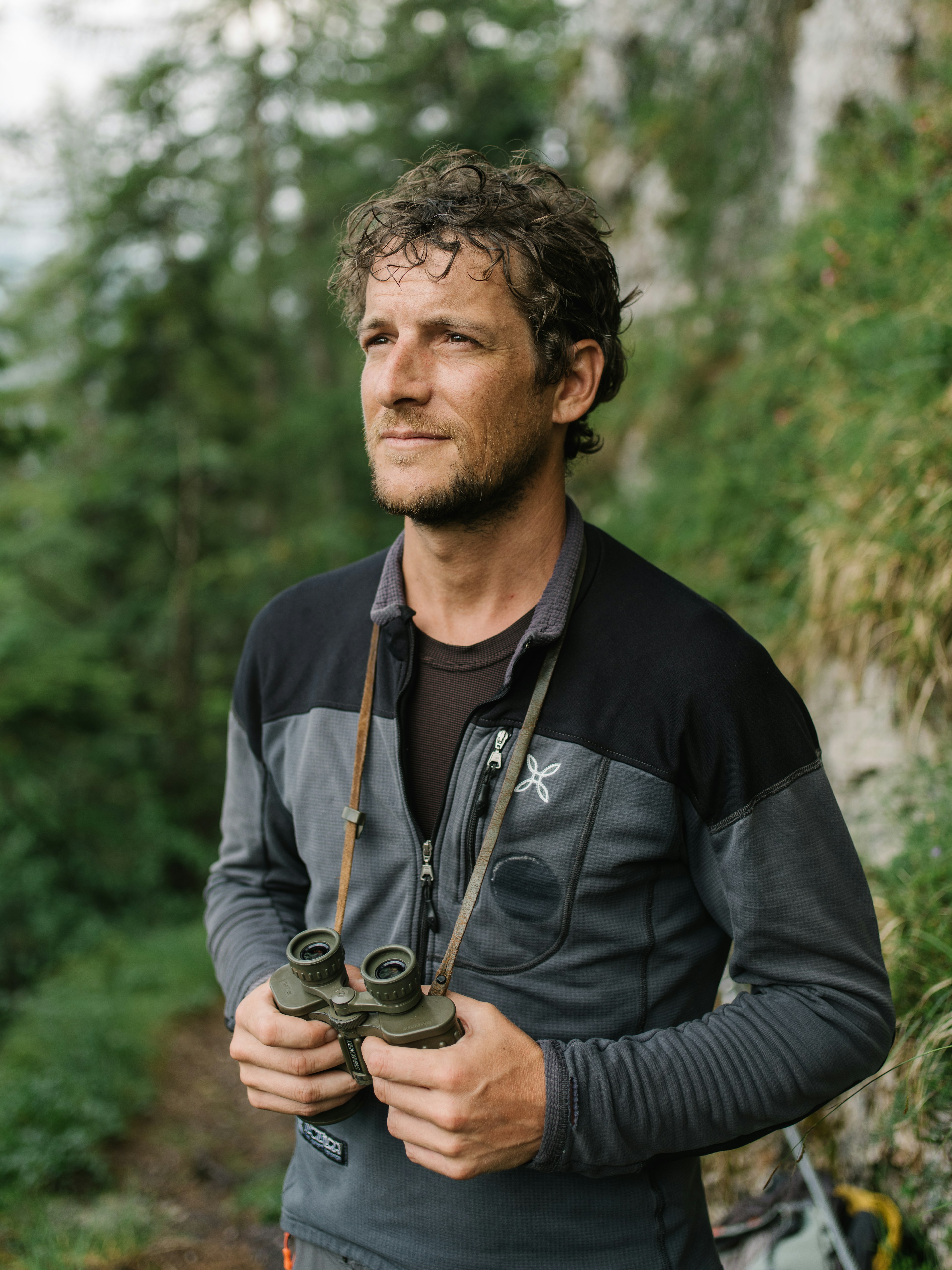 A man with curly hair holding binoculars