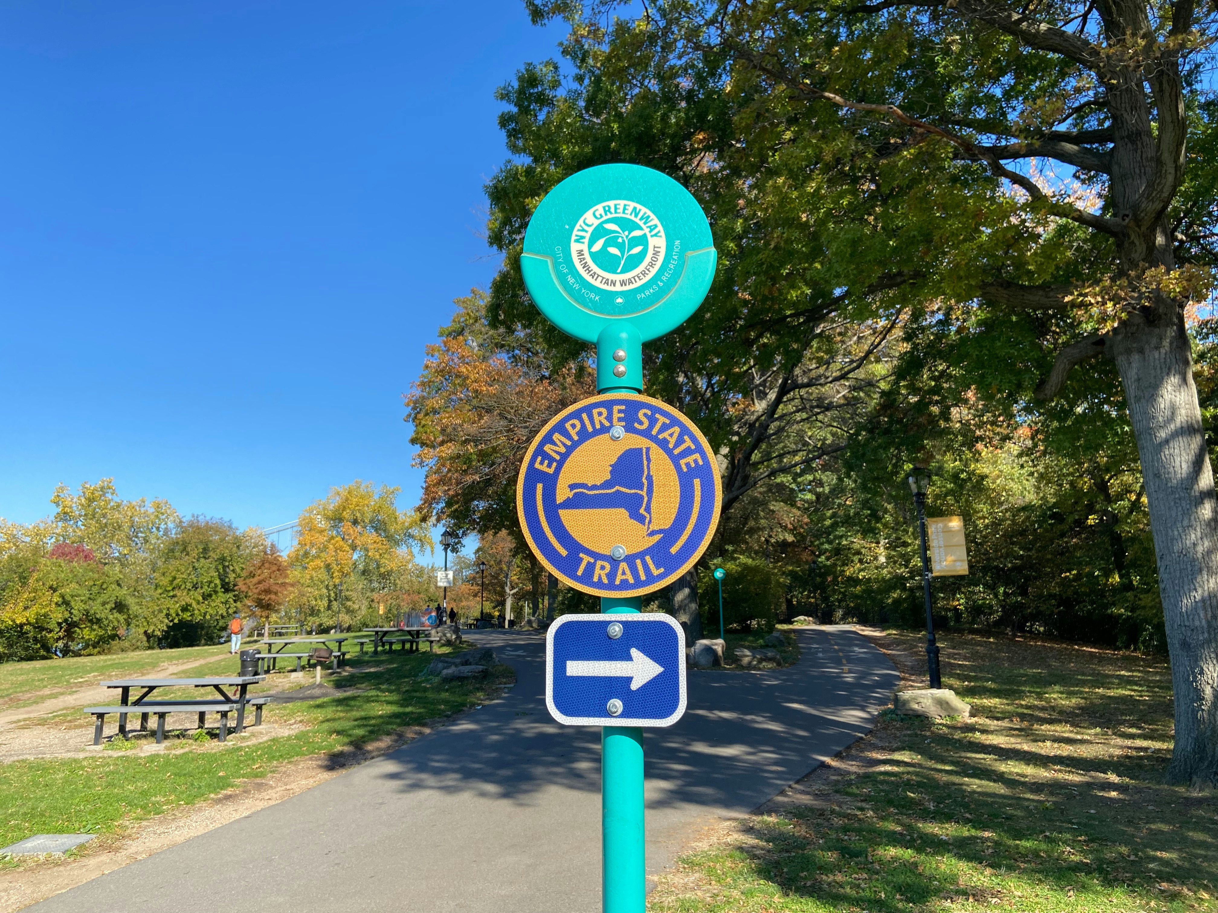 Signs for the NYC Greenway and Empire State Trail on a bicycle path in Riverside Park, Manhattan, New York City.