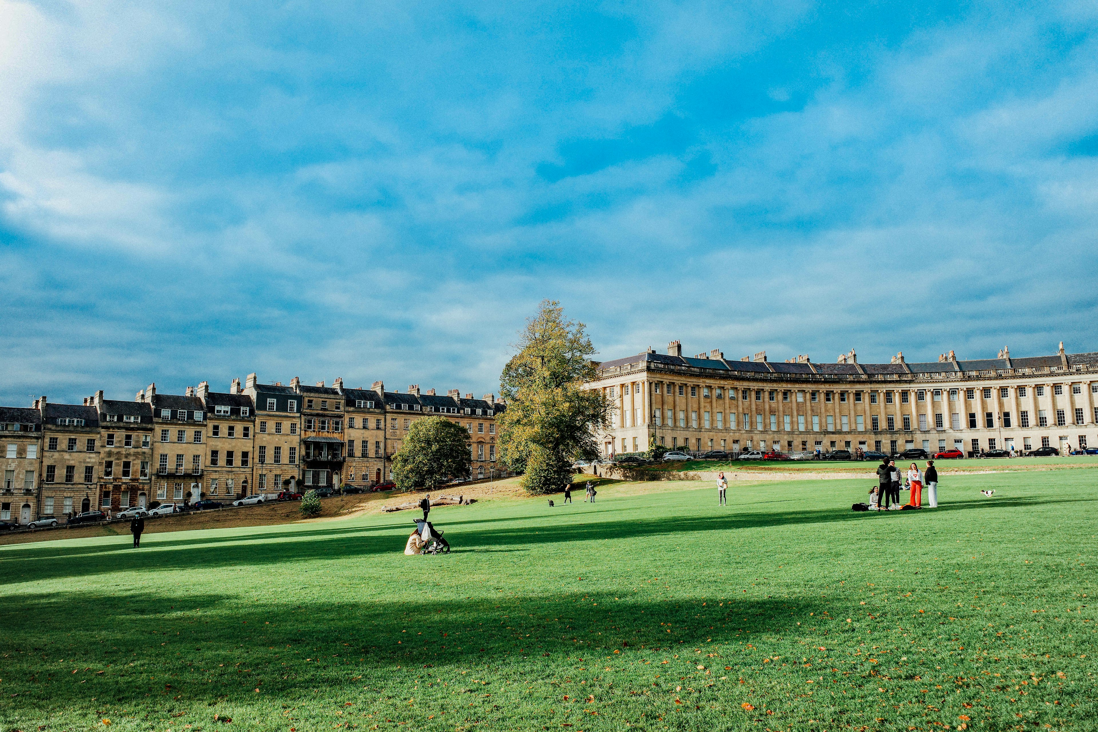 People enjoy a the sunny afternoon on the grass in front of the Royal Crescent, a curved line of honey-colored buildings in Bath, England.