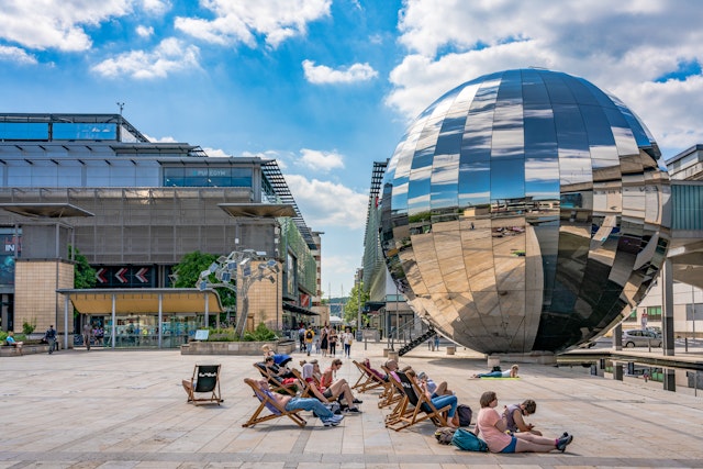 People sit in front of a large disco-ball-like sculpture at the We The Curious Museum in Bristol