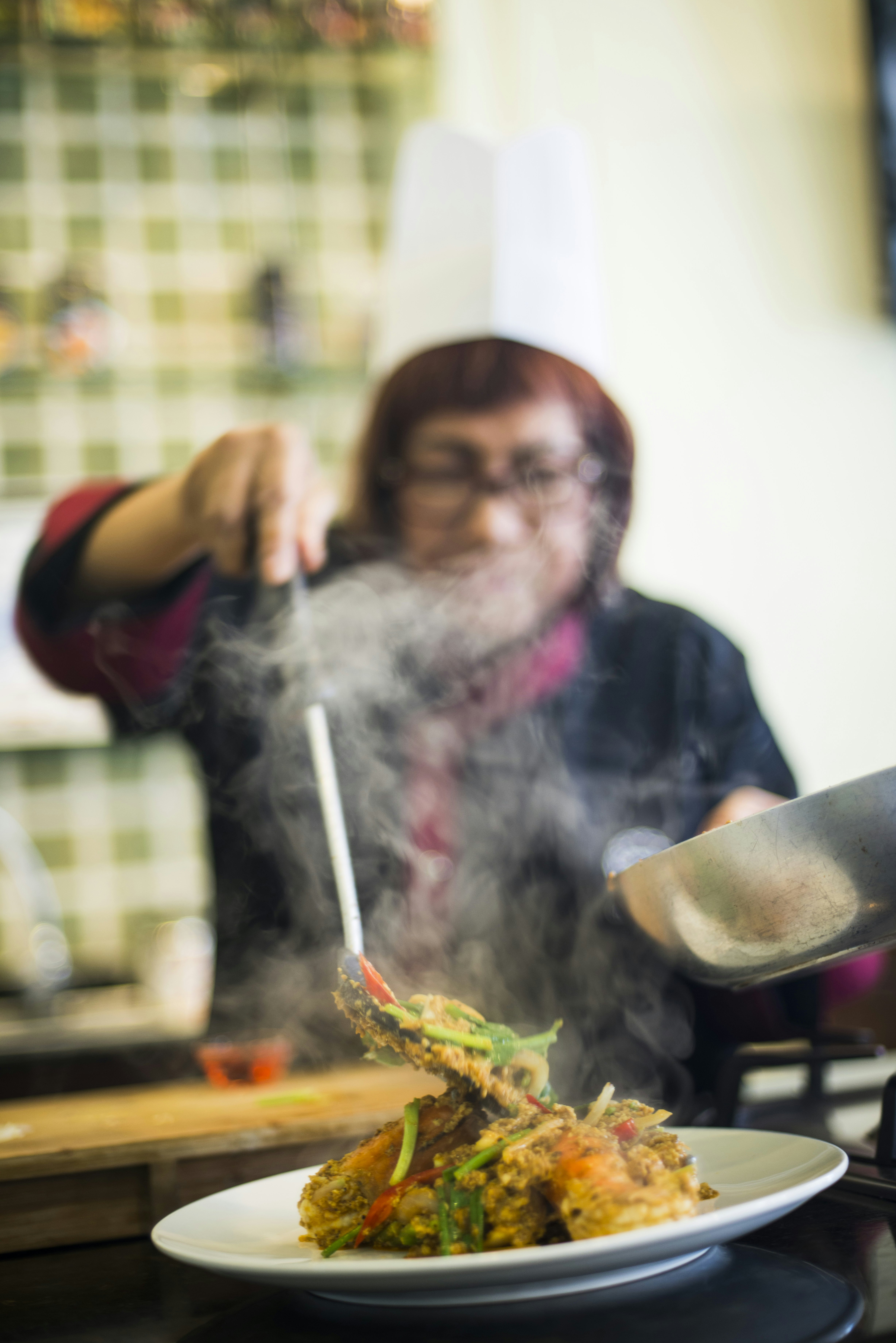 A chef serves a steaming dish of Thai food