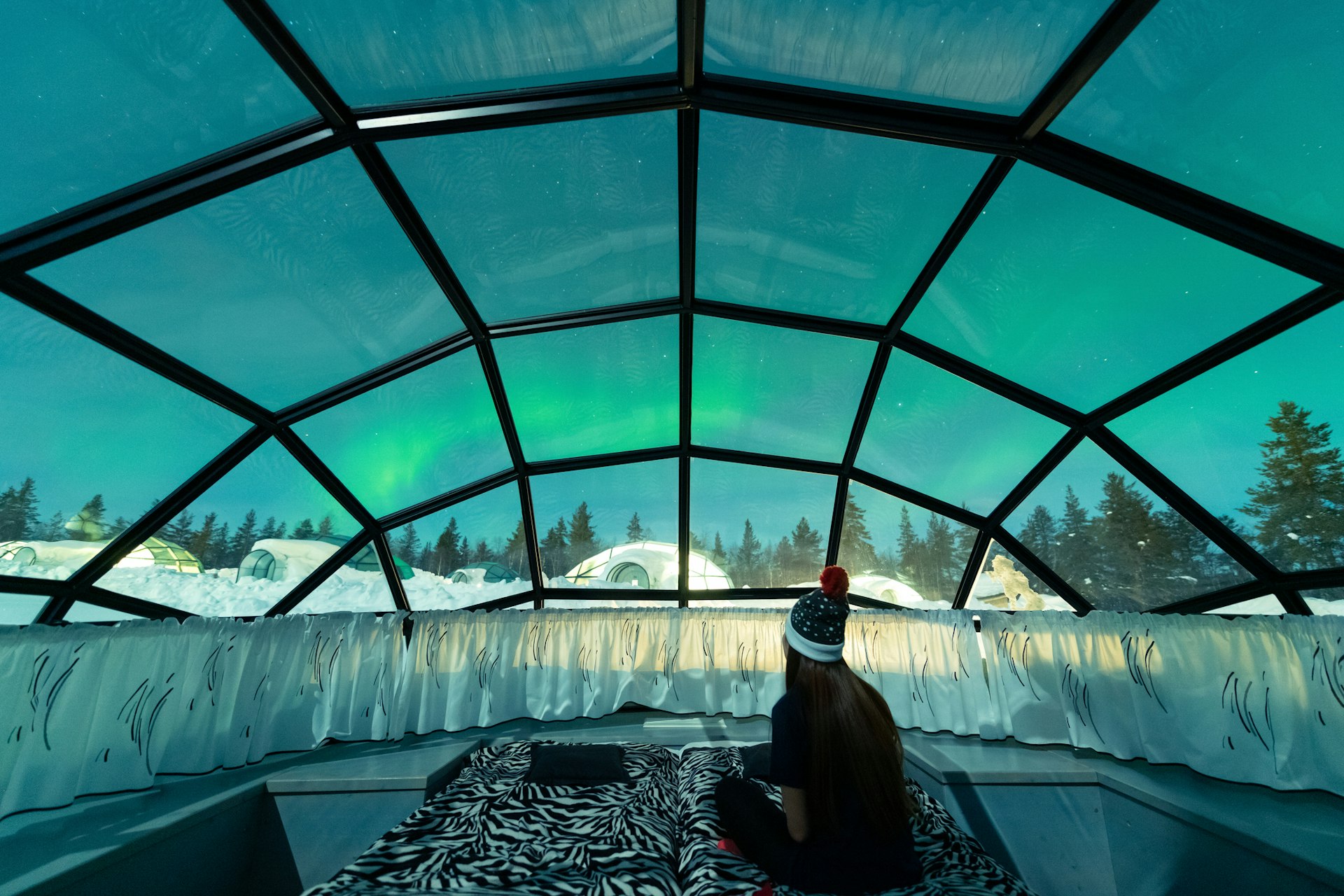 A woman watches the northern lights from inside a glass igloo in a resort in Finnish Lapland. 