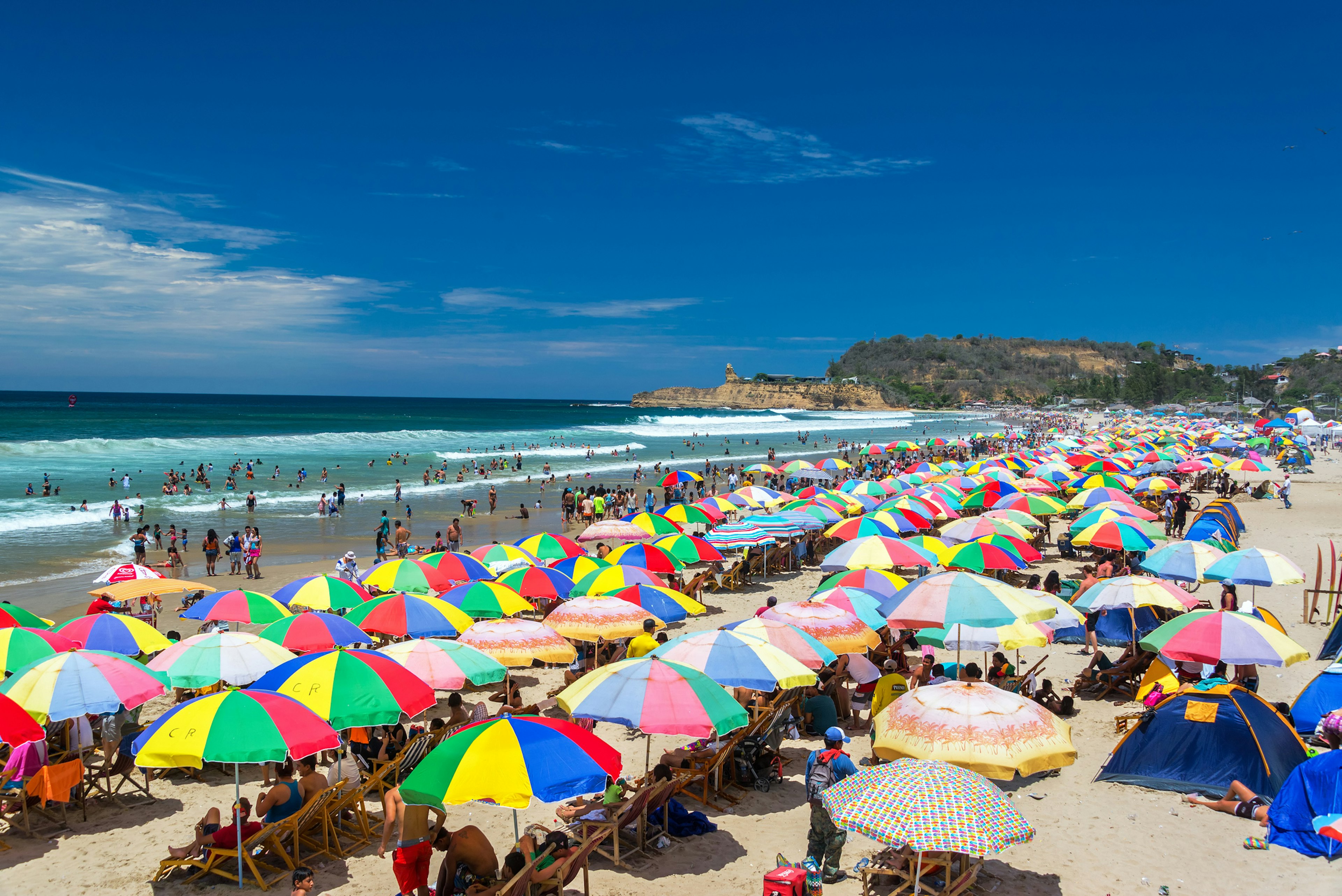 Packed Beach in Montanita, with people lounging under colorful sun shades