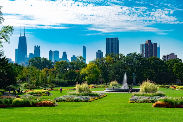 A large garden scene with plants and a fountain in Lincoln Park, Chicago, with the city skyline towering beyond