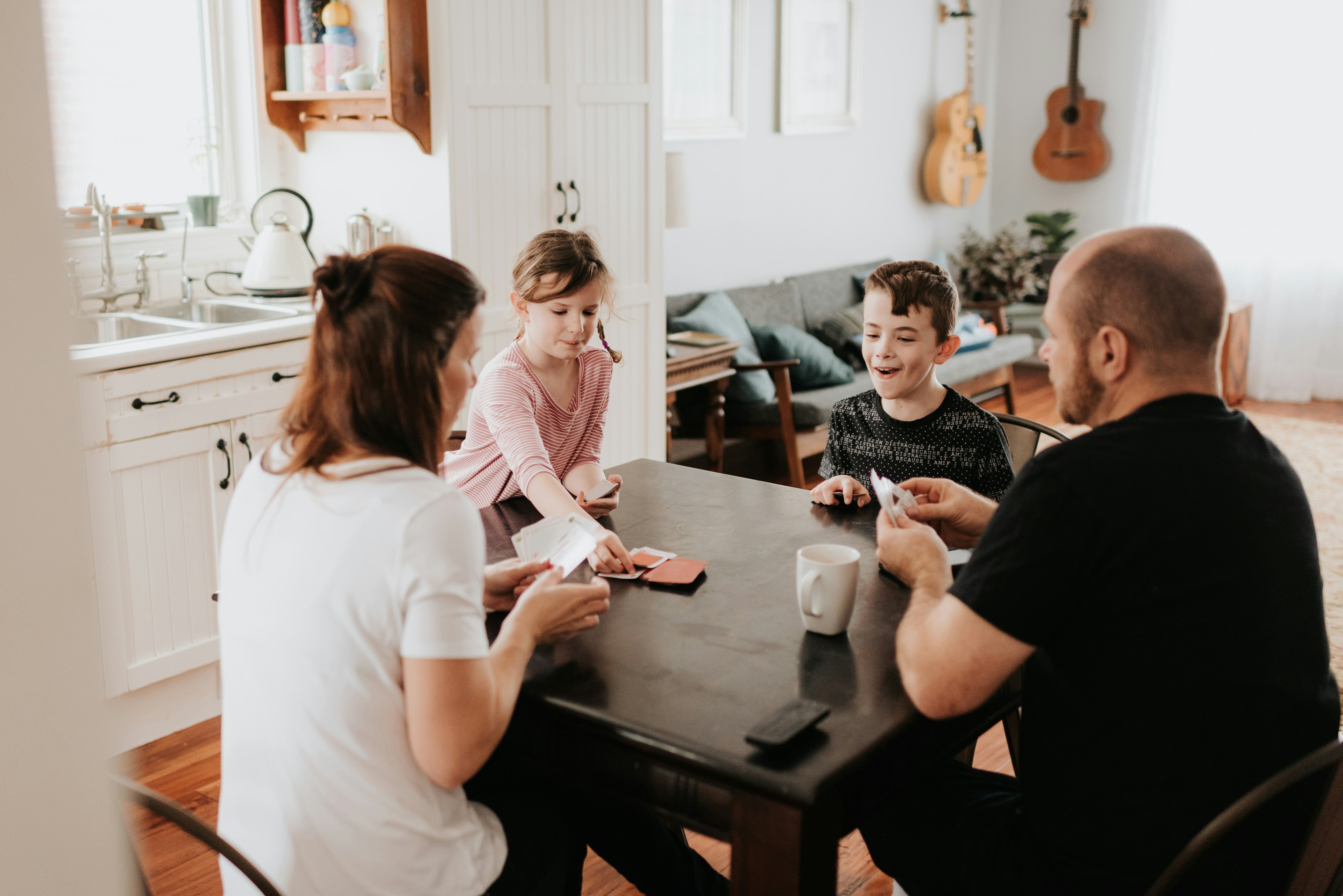 Family of four playing cards in kitchen