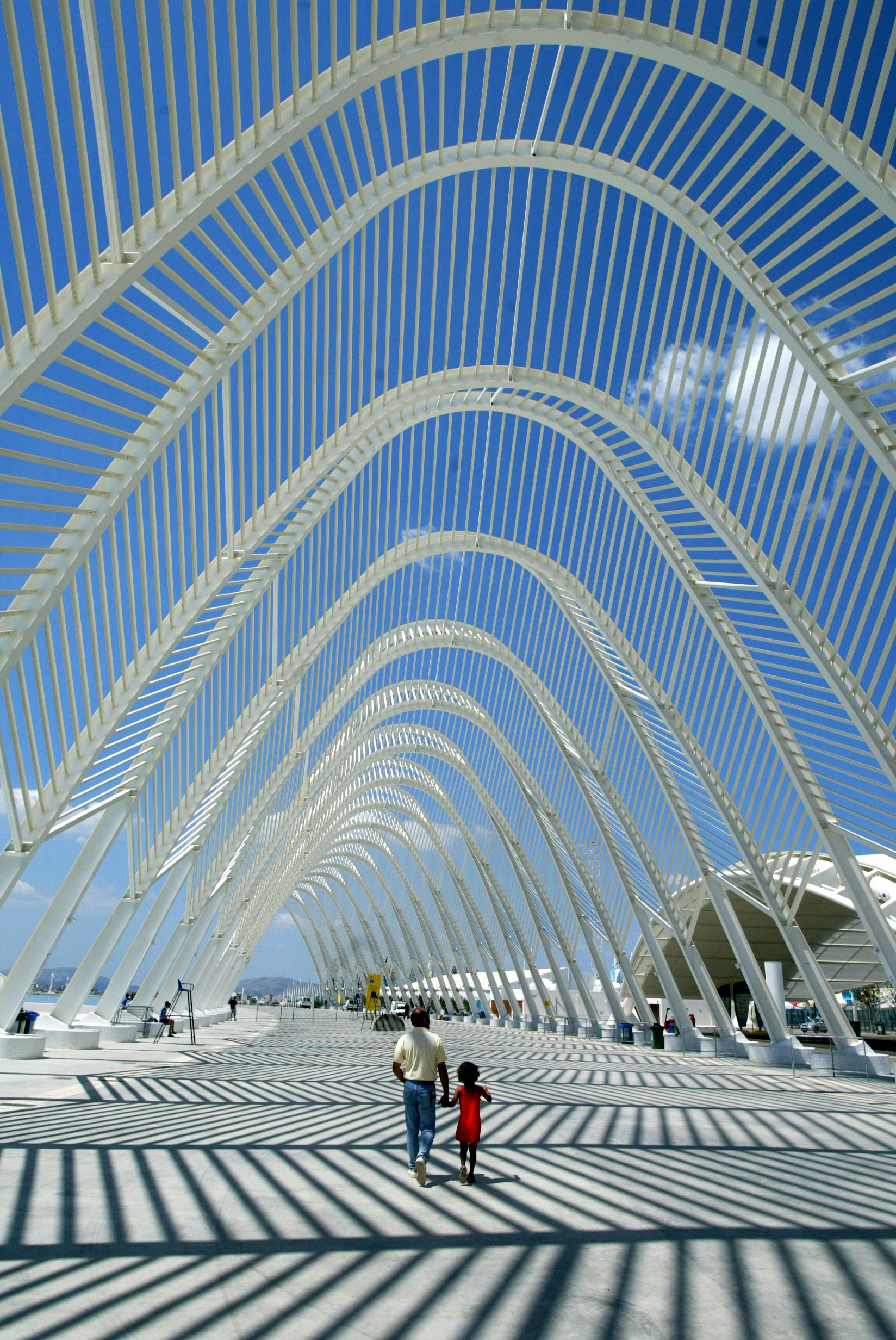 A father and his daughter tour the Athens Olympic Sports Complex and walk beneath Santiago Calatrava's triumphant architectural arcs