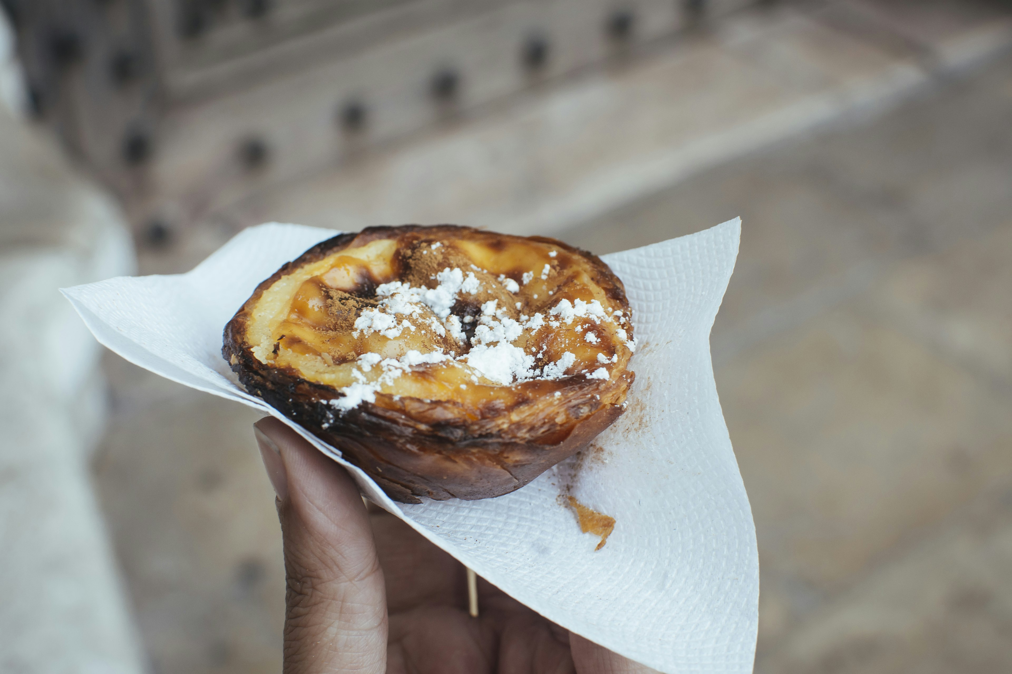 Hand holding a traditional Portuguese egg custard tart