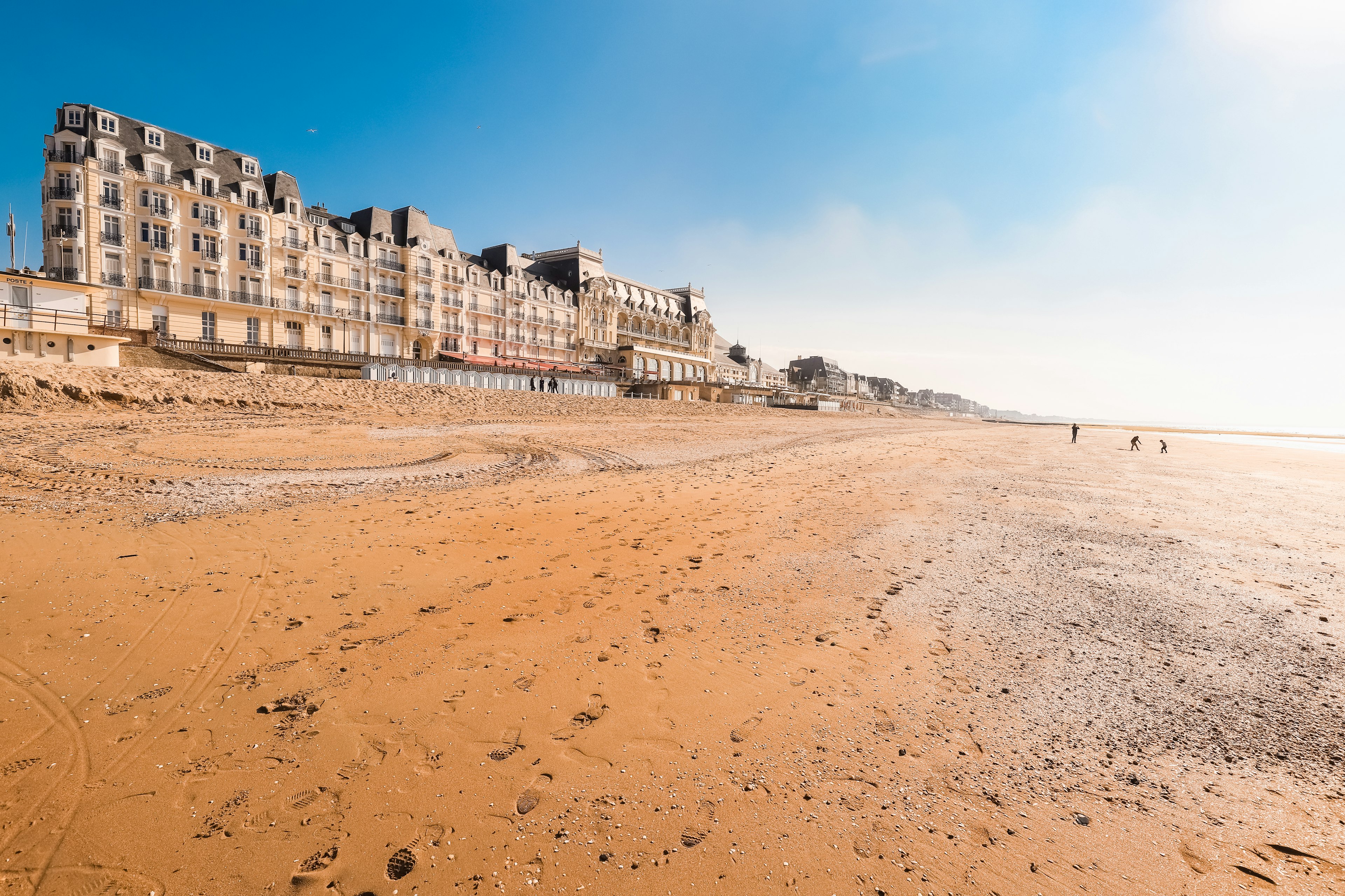 A wide, empty sandy Beach with buildings dating from the early 20th century lining the seafront