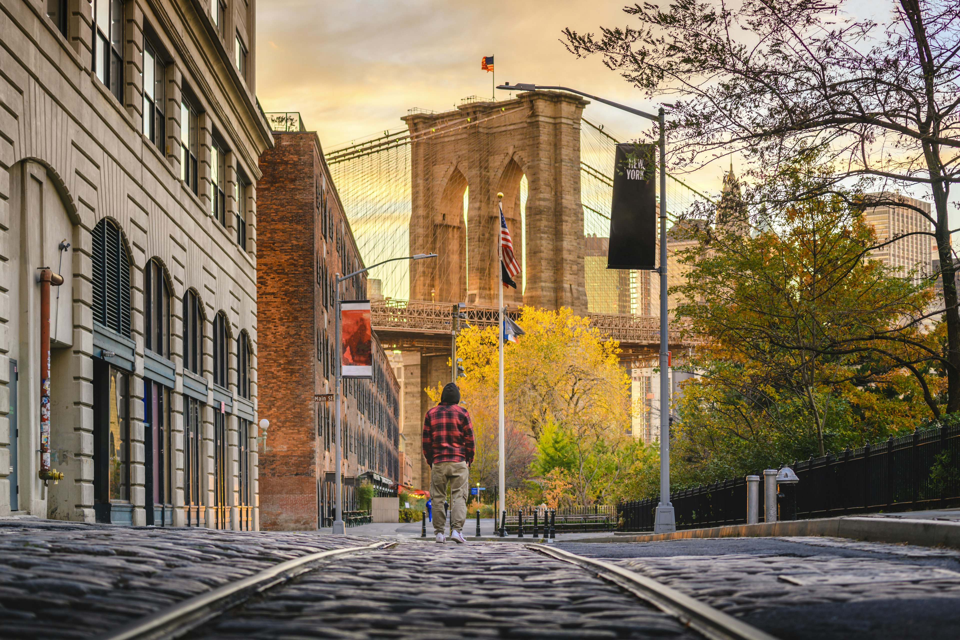 Man walking in Brooklyn admiring the Brooklyn Bridge at sunset, New York City