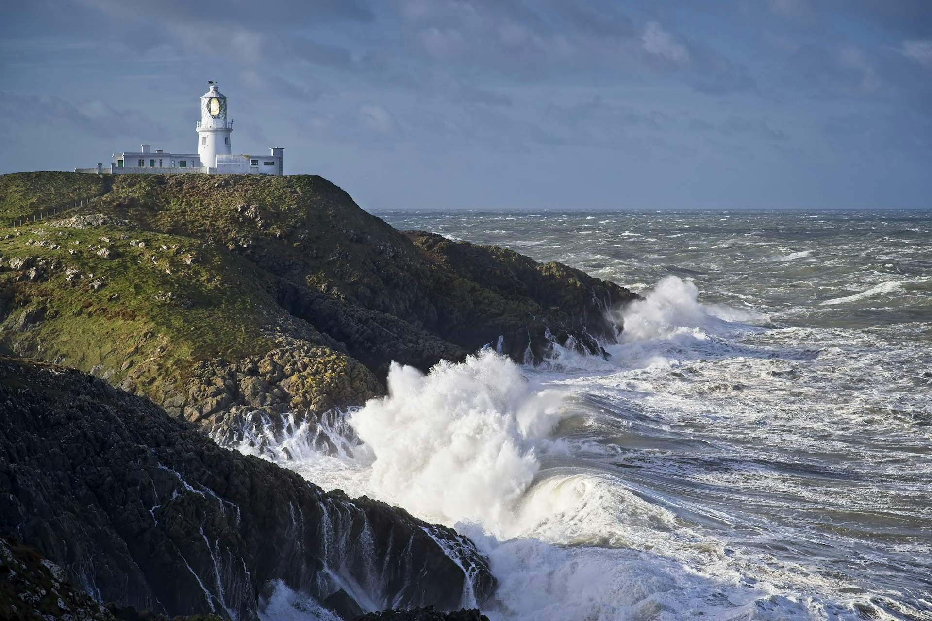 Waves hit the rocky coast below Strumble Head lighthouse, Wales