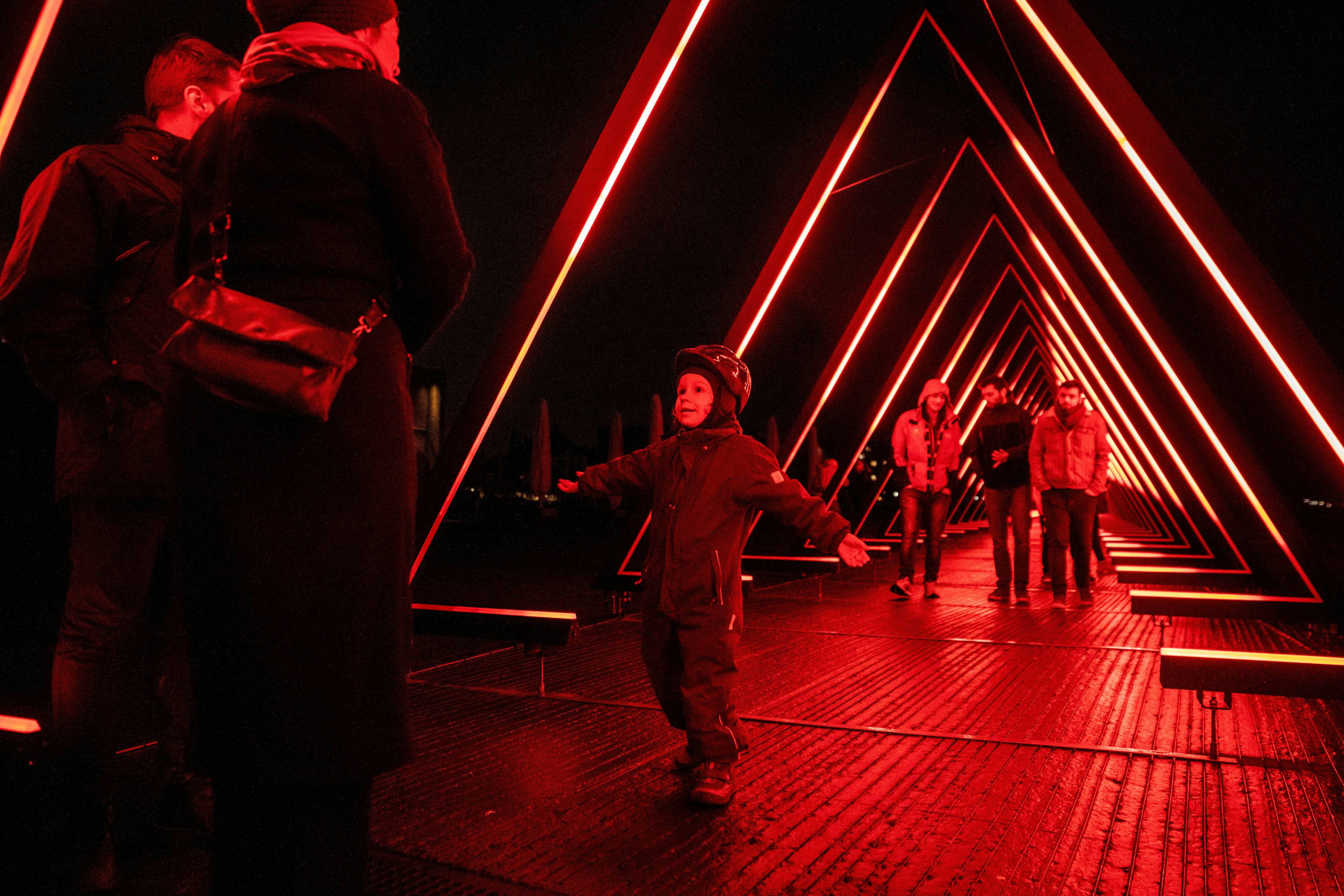 Visitors walk by and under a illuminated installation in red at the  light festival in Copenhagen