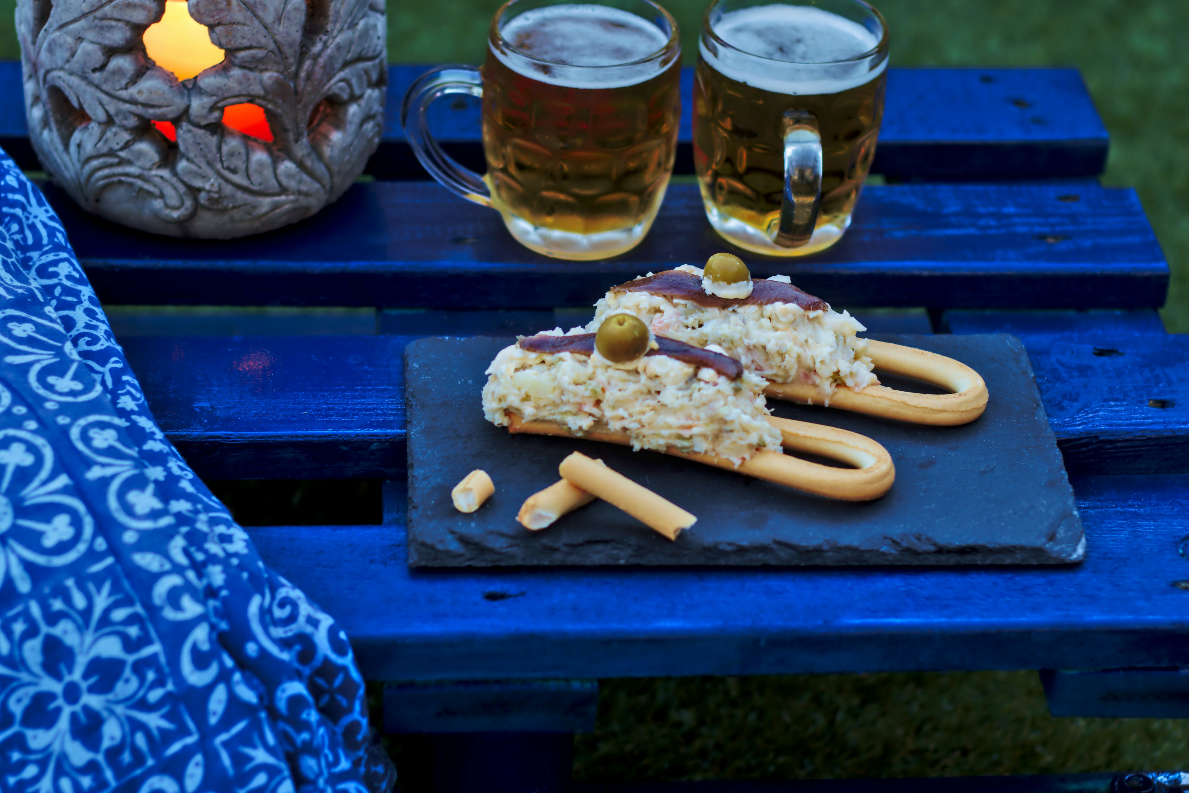 Marinera with two beers in the background. Marinera is a Russian salad cover on a bread roll with anchovy and olives, typical of Murcia, foods from Spain