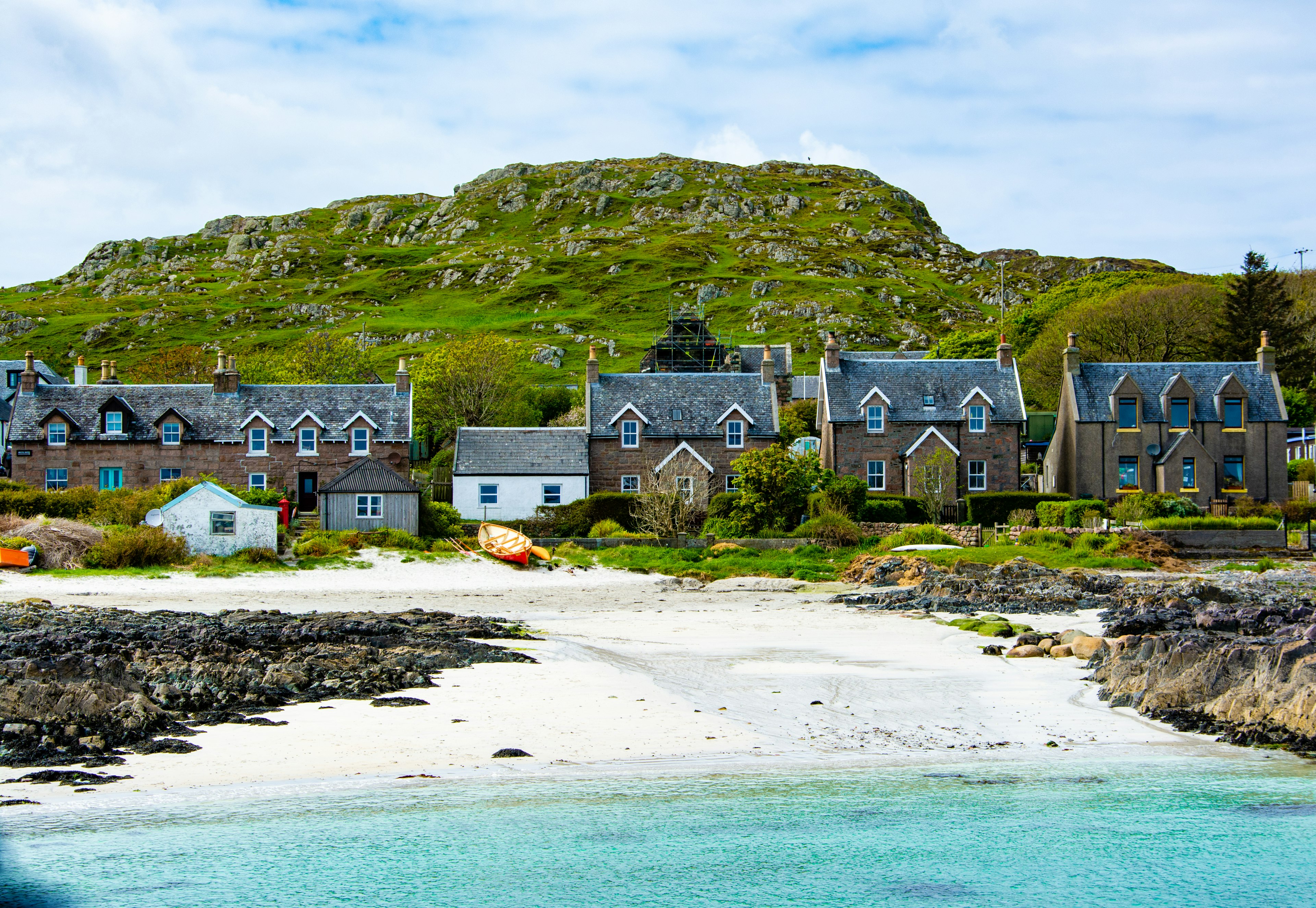 Houses by the beach under a cloudy blue sky in Iona, Scotland