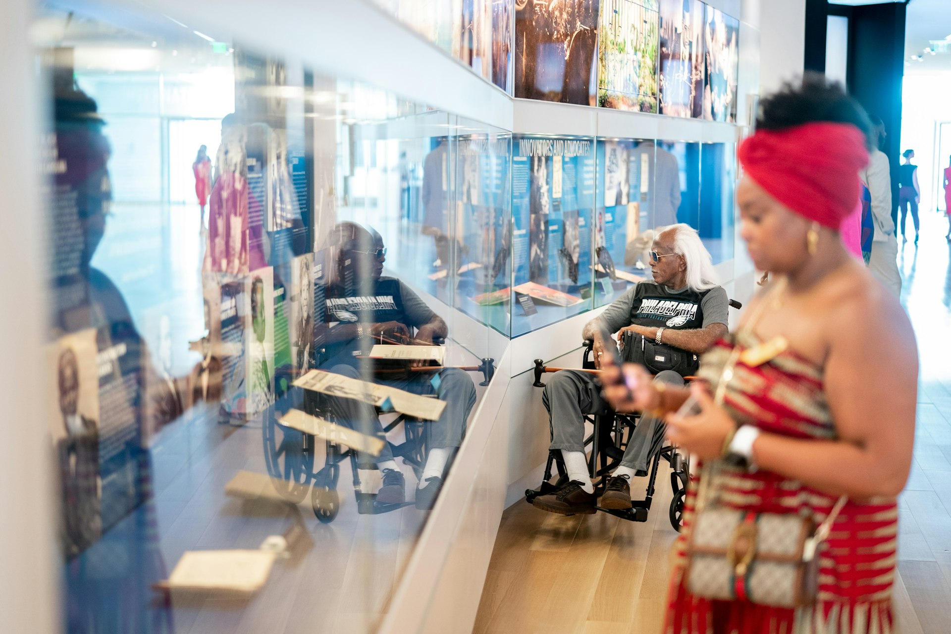 A man in a wheelchair and a woman look at exhibits in a glass case at the International African American Museum, Charleston, SC