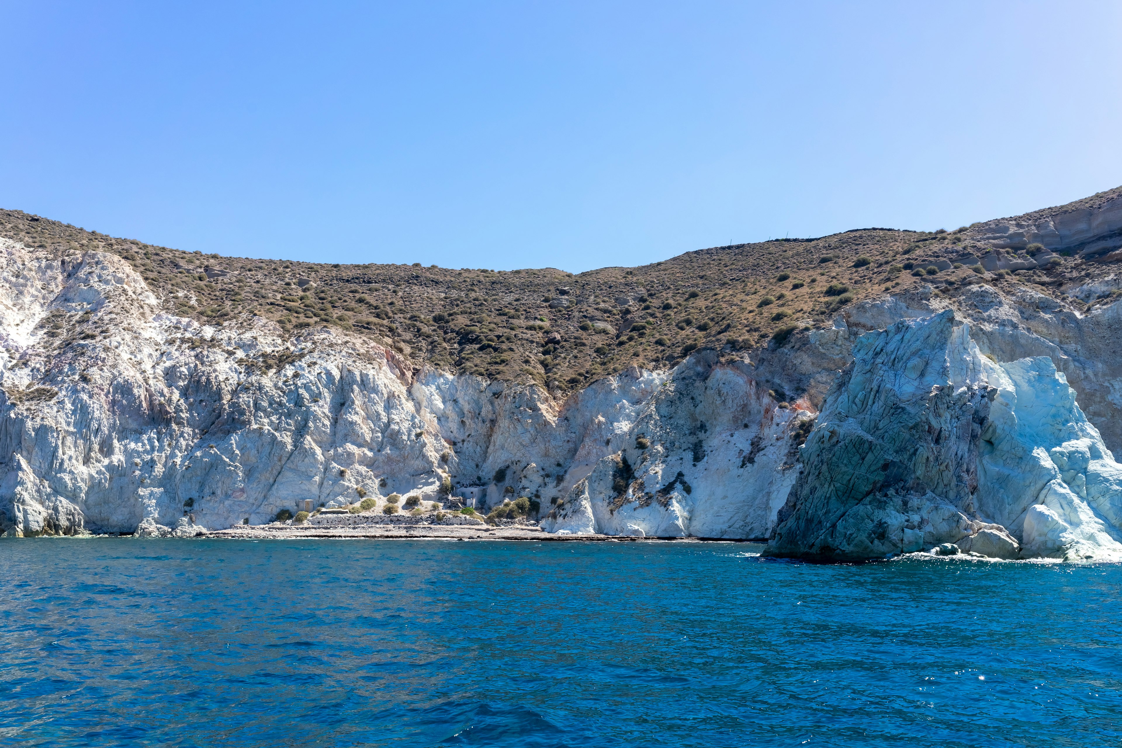 A shot taken out at sea looking towards some white chalk cliffs with a small beach at the foot of them