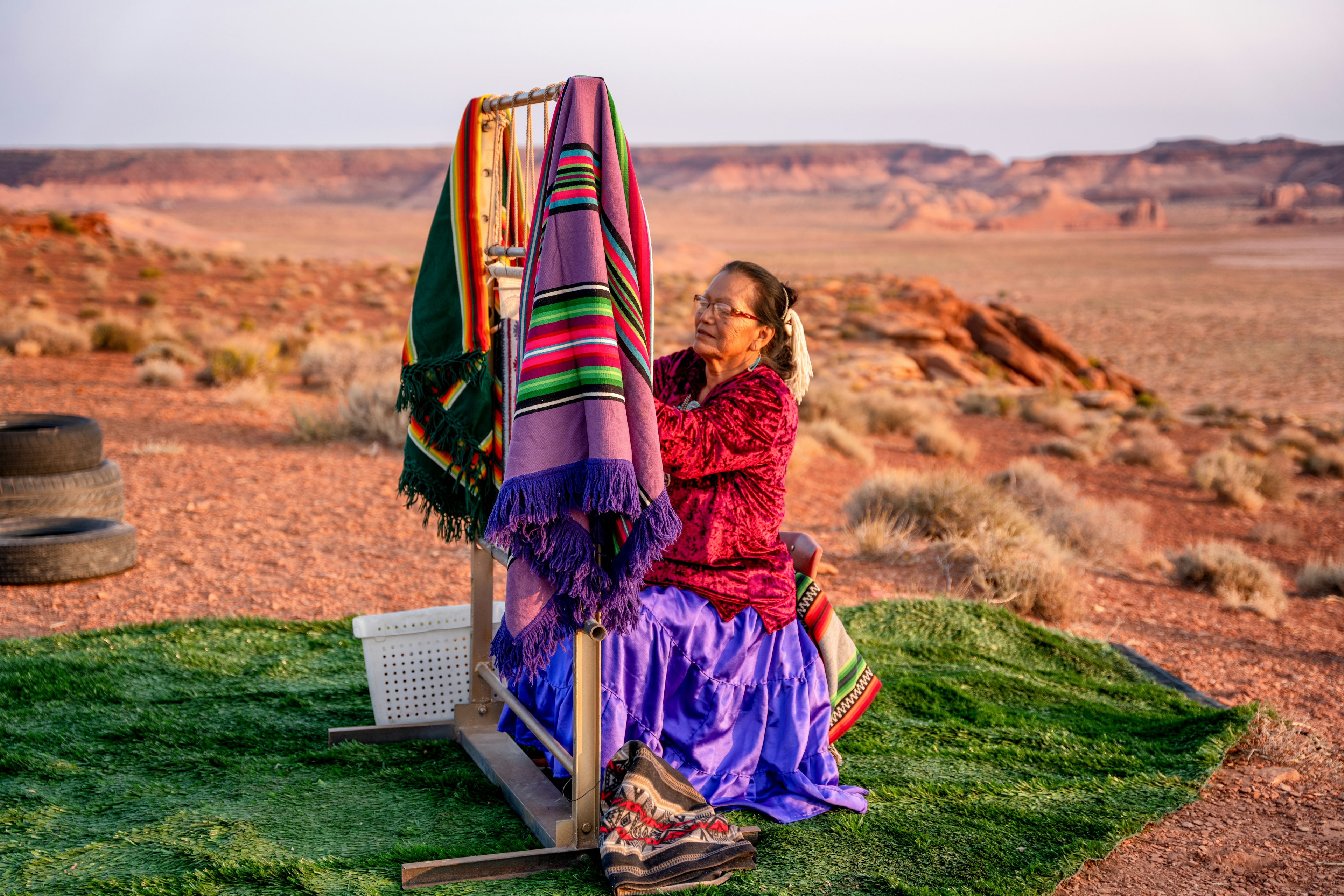 Elderly Navajo Woman Weaving a Traditional Blanket or Rug on an Authentic Native American Loom in the Desert at Dusk near the Monument Valley Tribal Park in Northern Arizona