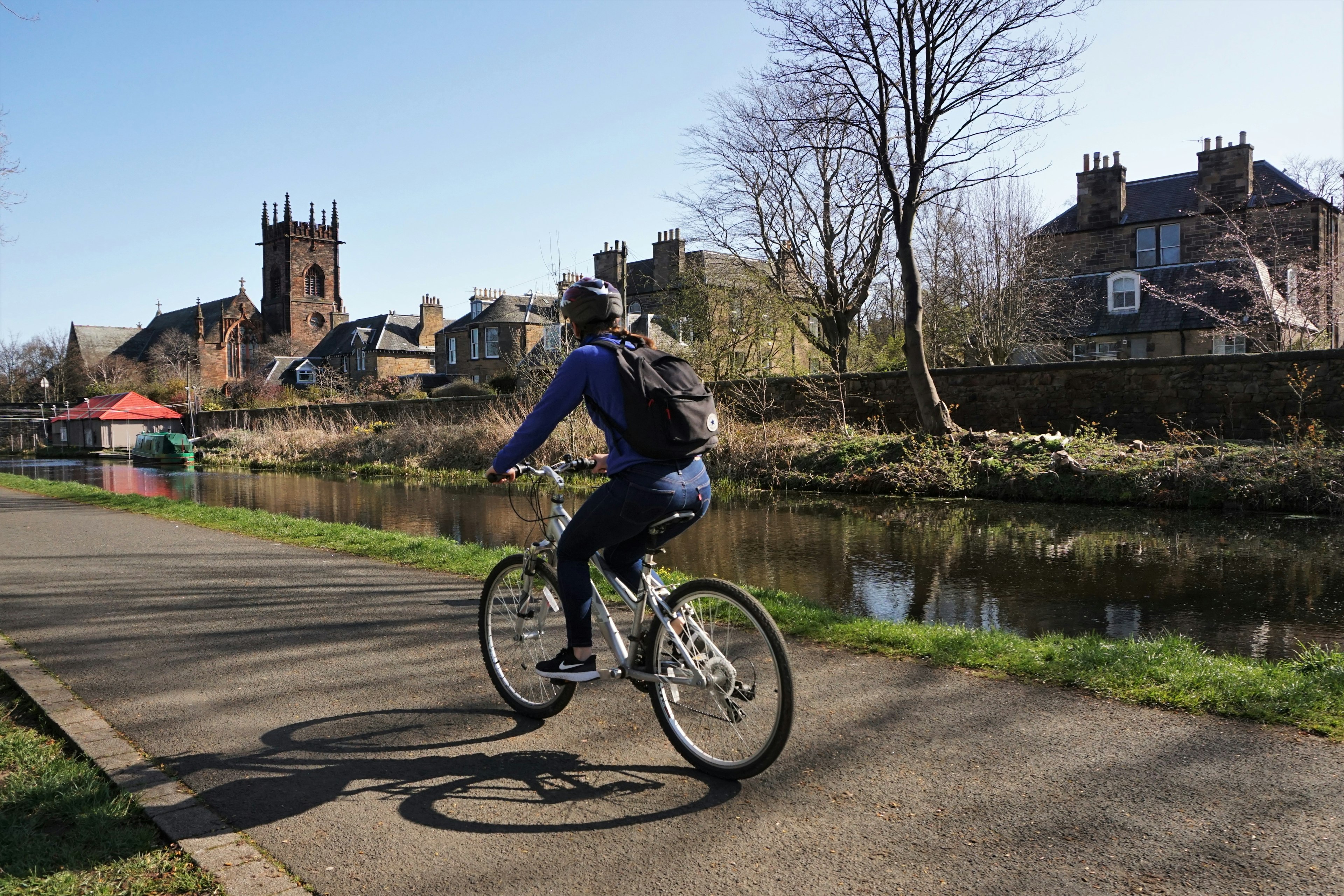 A cyclist following the calm path beside the Union Canal towards central Edinburgh