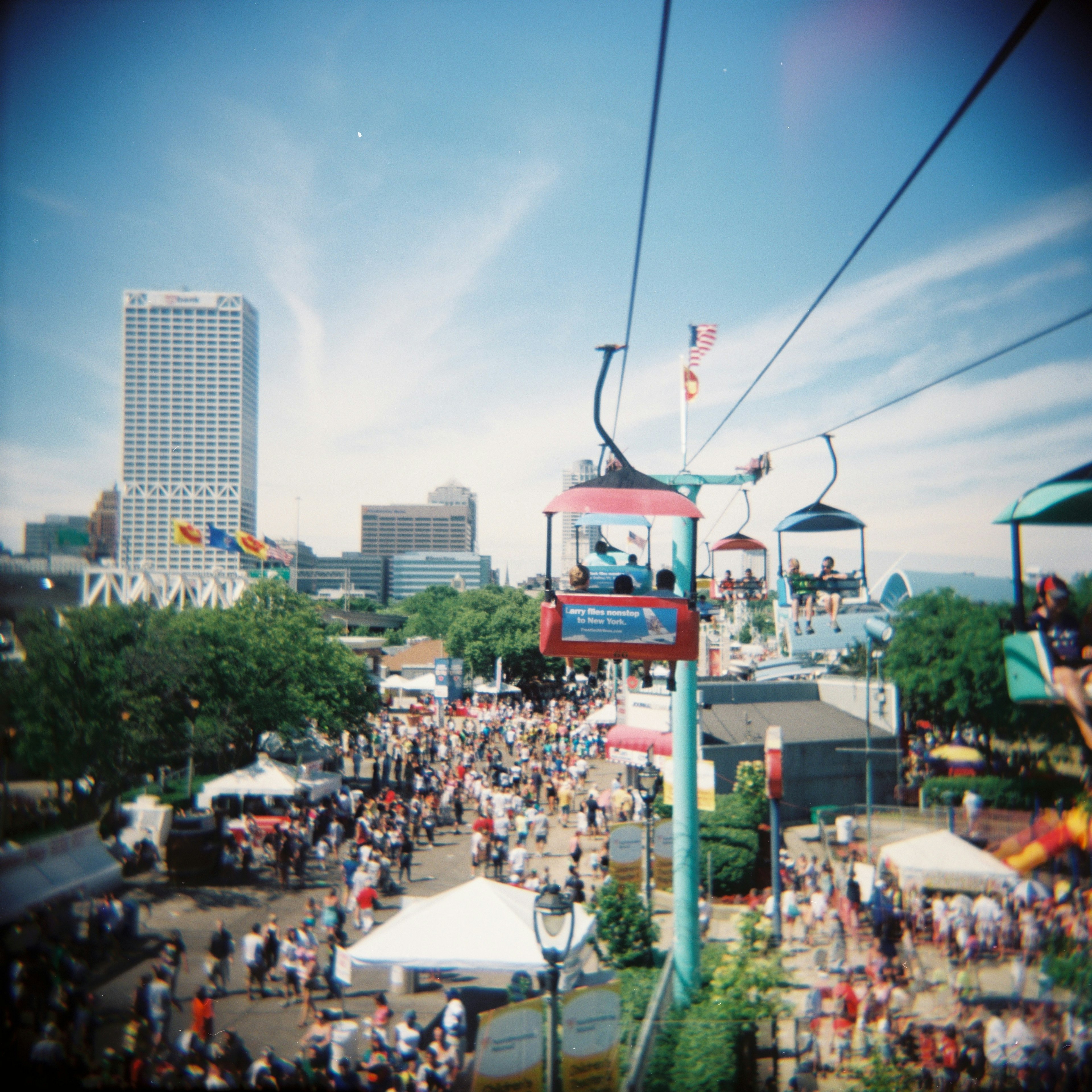 A gondola at Henry Maier Festival Park soars above crowds below and the skyline in the distance during Summerfest, Milwaukee, Wisconsin, USA.