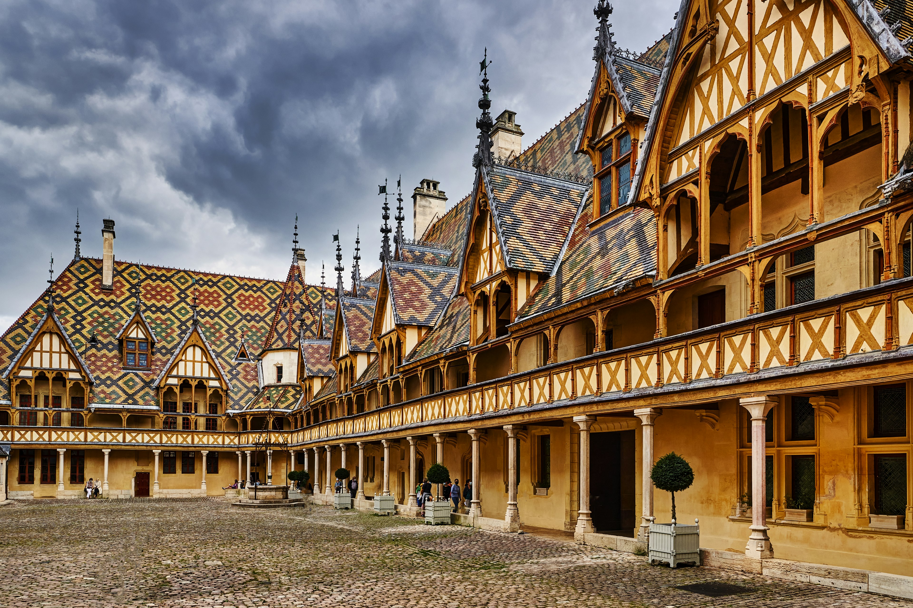 The interior courtyard of an historic building, with yellow, red and black tiles on the steep roofs