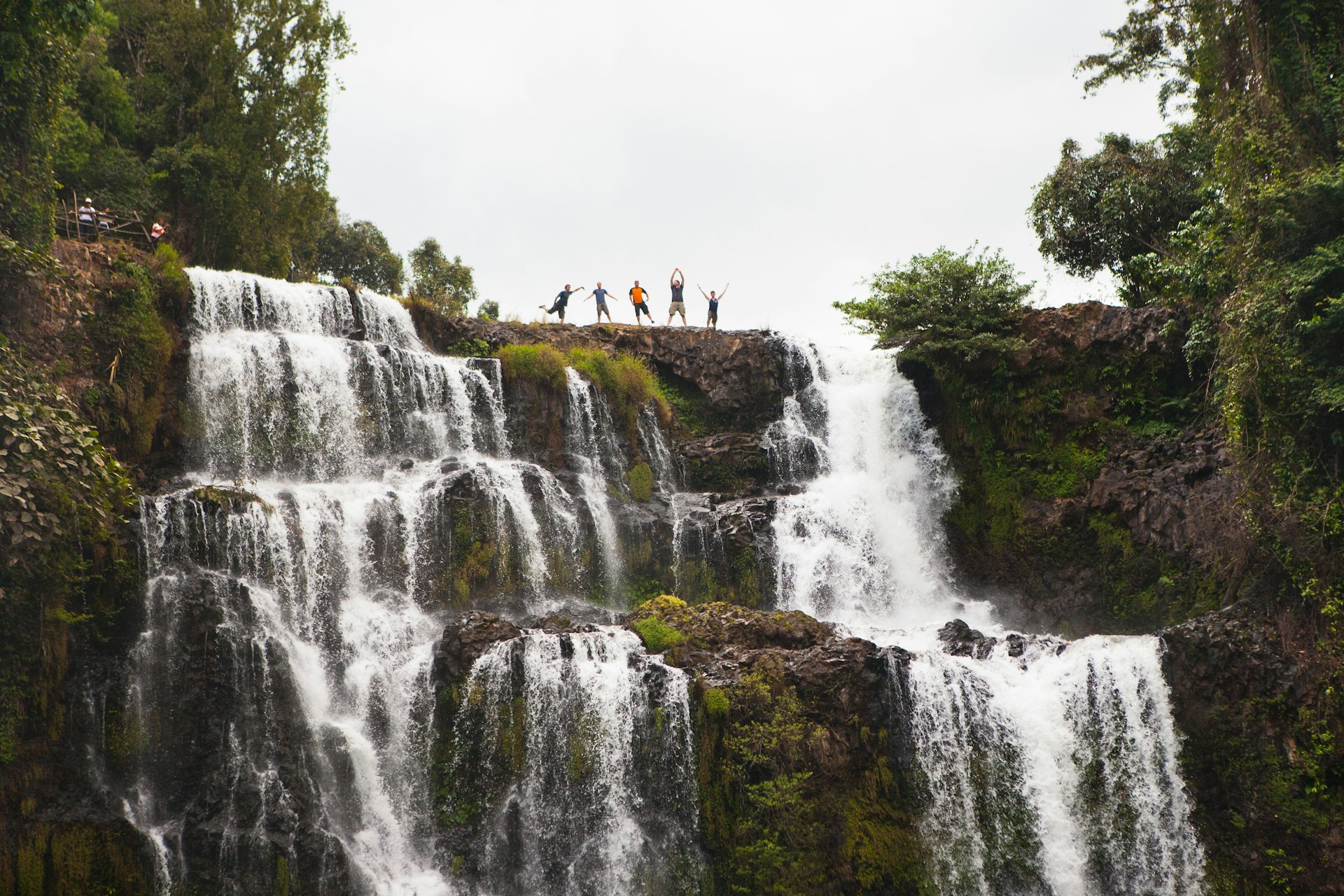 Five people strike a pose at the top of the mighty Tad Yuang waterfalls, Bolaven Plateau, Laos 