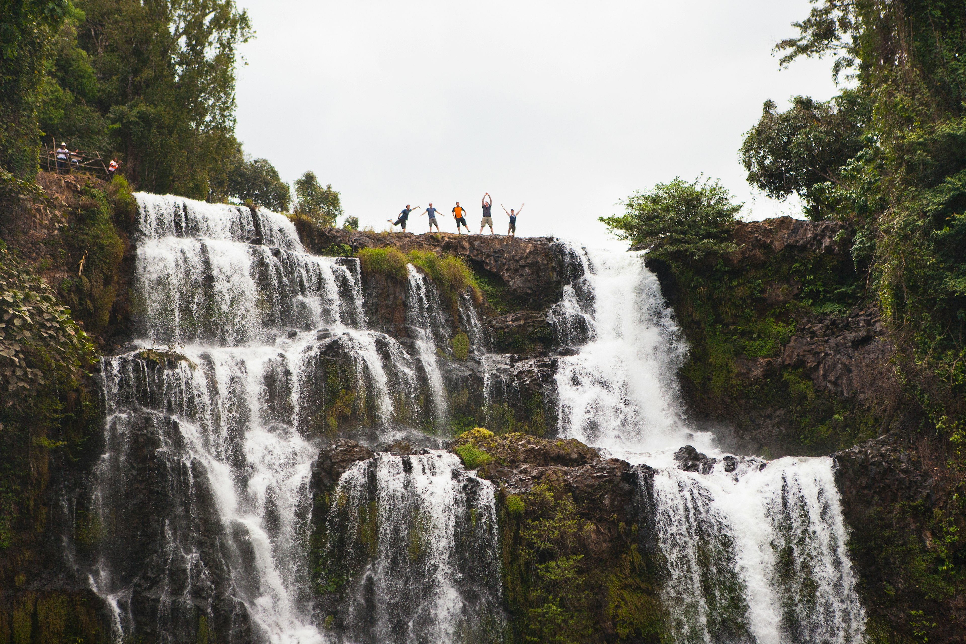 Five people strike a pose at the top of the mighty Tad Yuang waterfalls, Bolaven Plateau, Laos