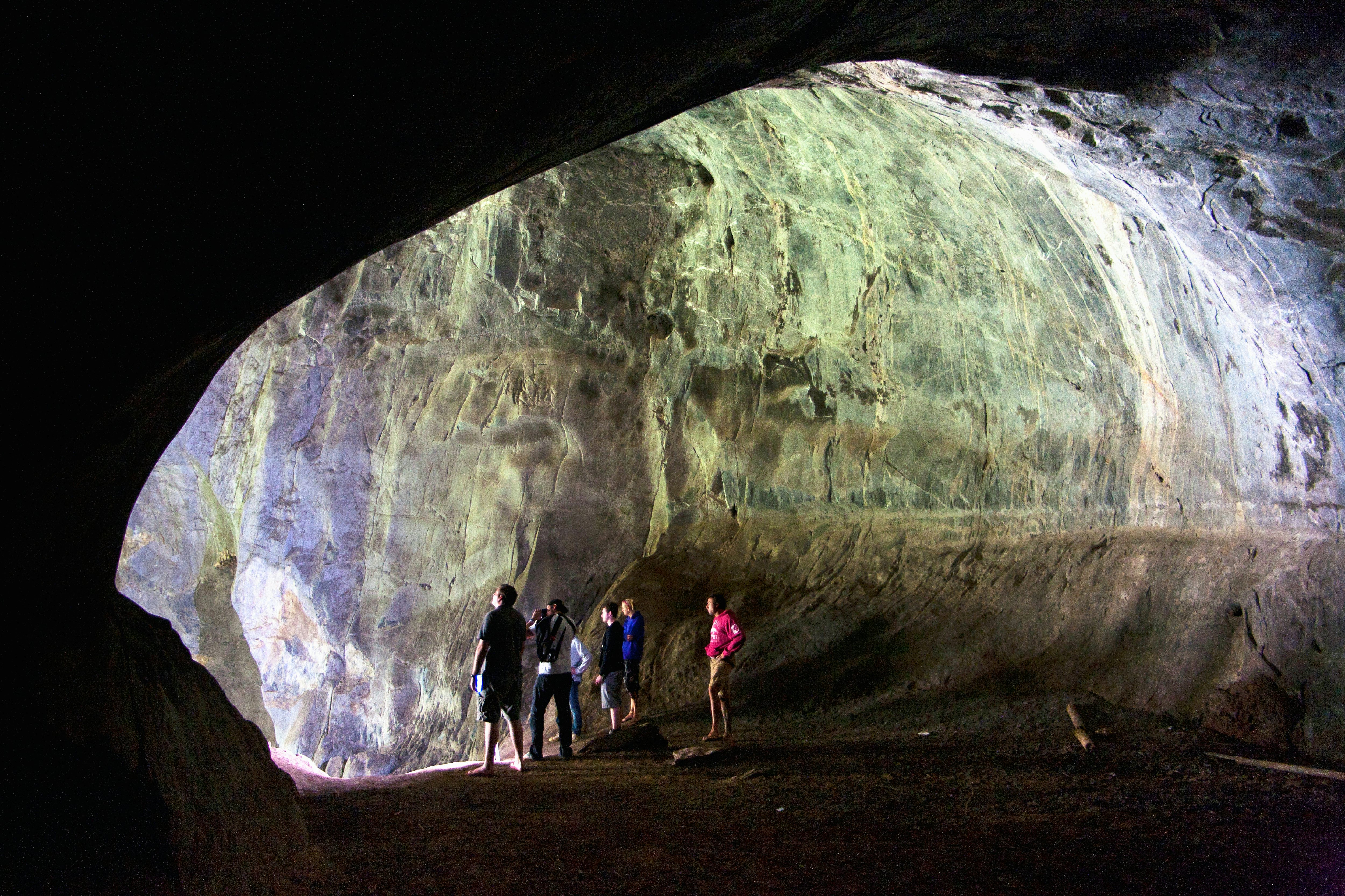 A group of people illuminated by daylight at the mouth of the Patok Cave near Nong Khiaw, Laos