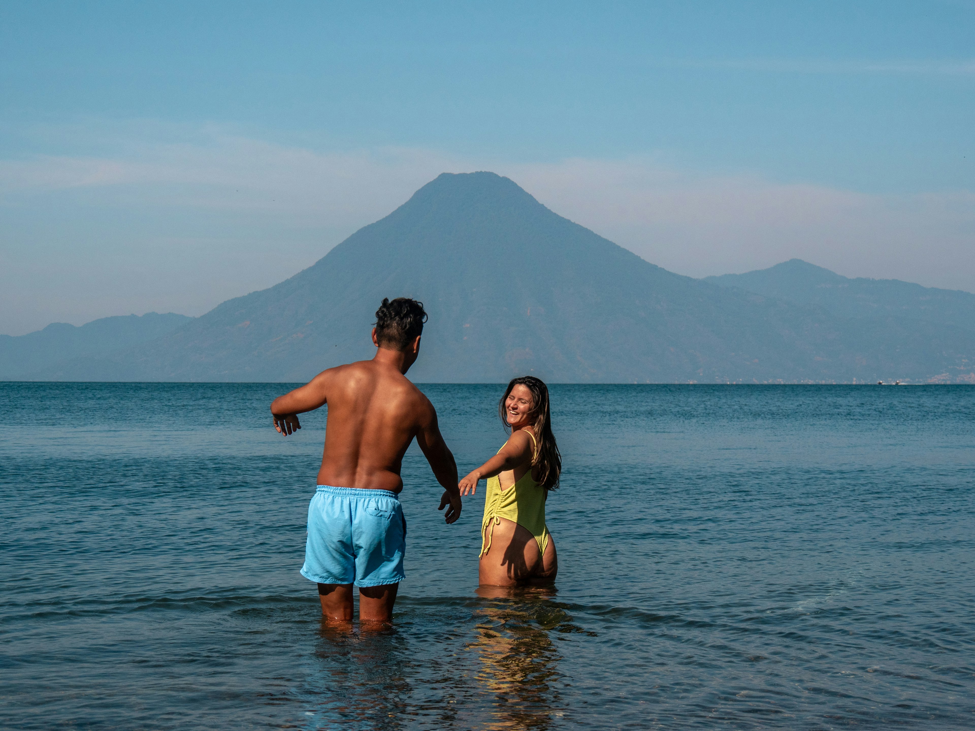 A man and woman wade into Lake Atitlan