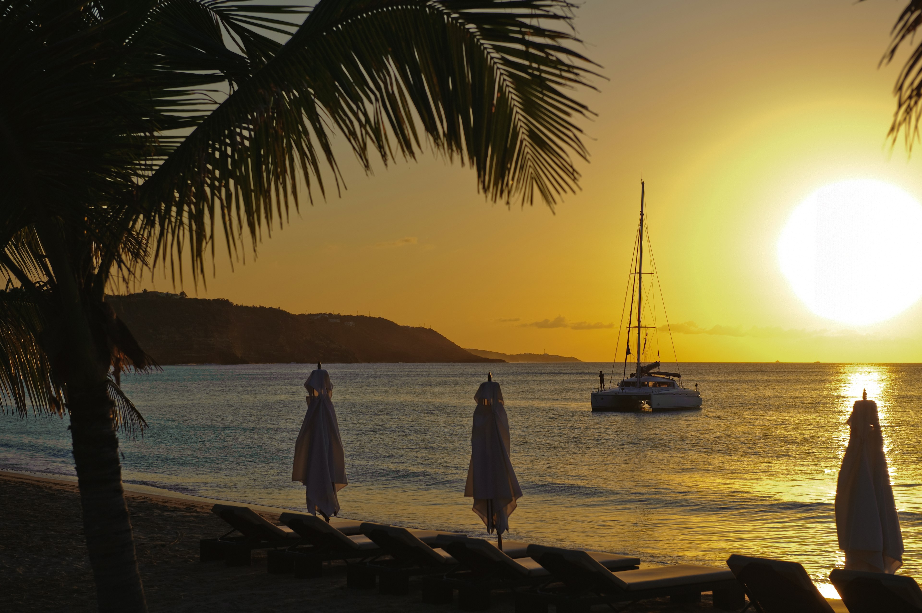 Yellow sunset at the beach with a sailboat in view