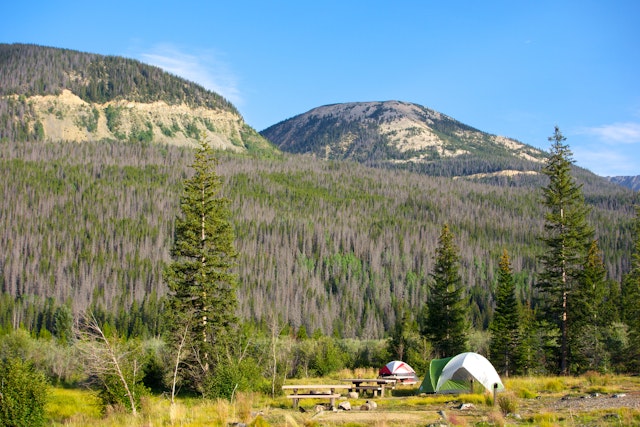 Tent at a campground in Colorado backed by mountain ridges