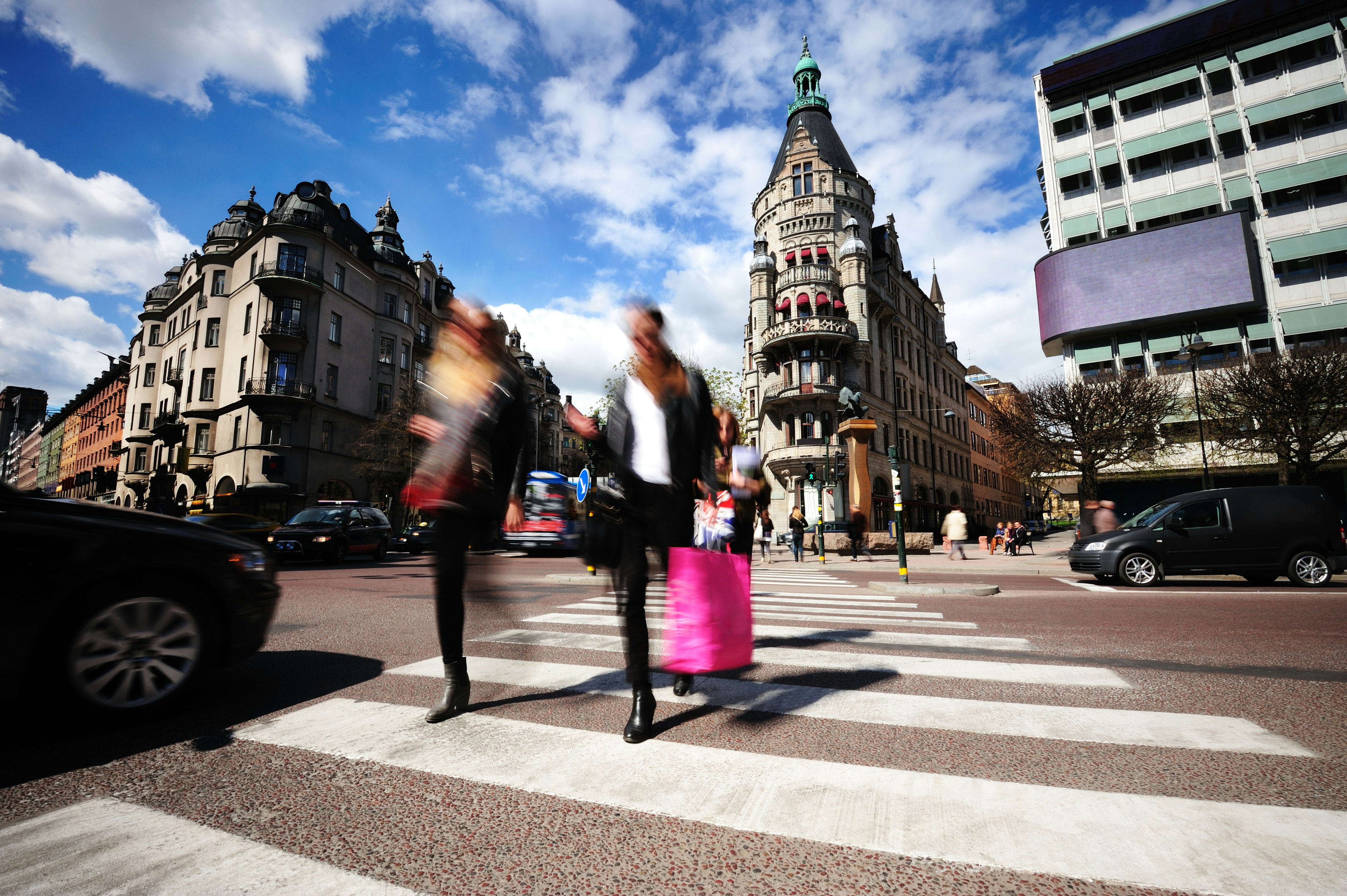 A blurred image of people with shopping bags crossing a zebra-striped crossing in Östermalm, Stockholm