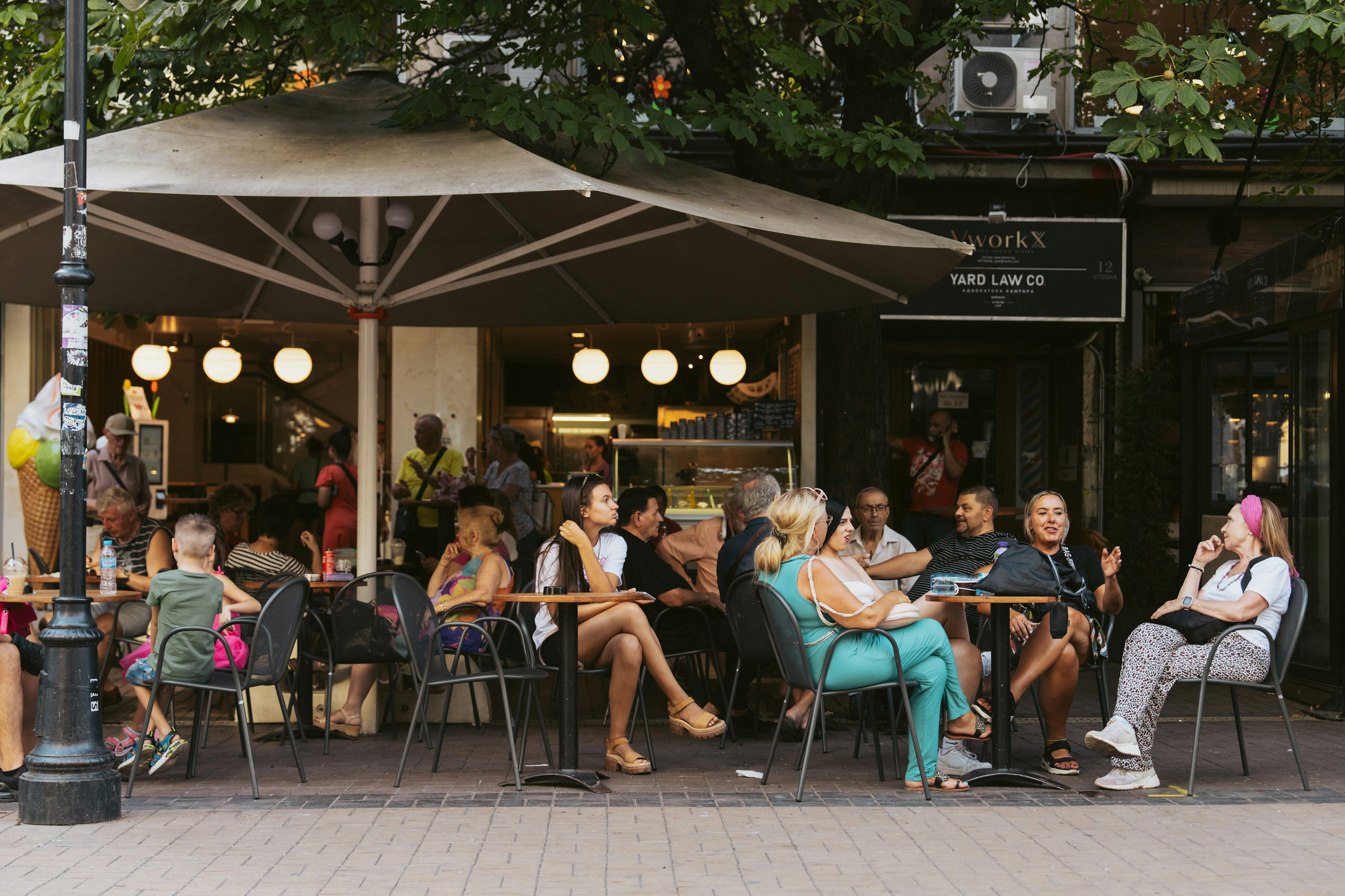 People sit at outdoor cafes on Vitosha Boulevard on a warm day in Sofia, Bulgaria