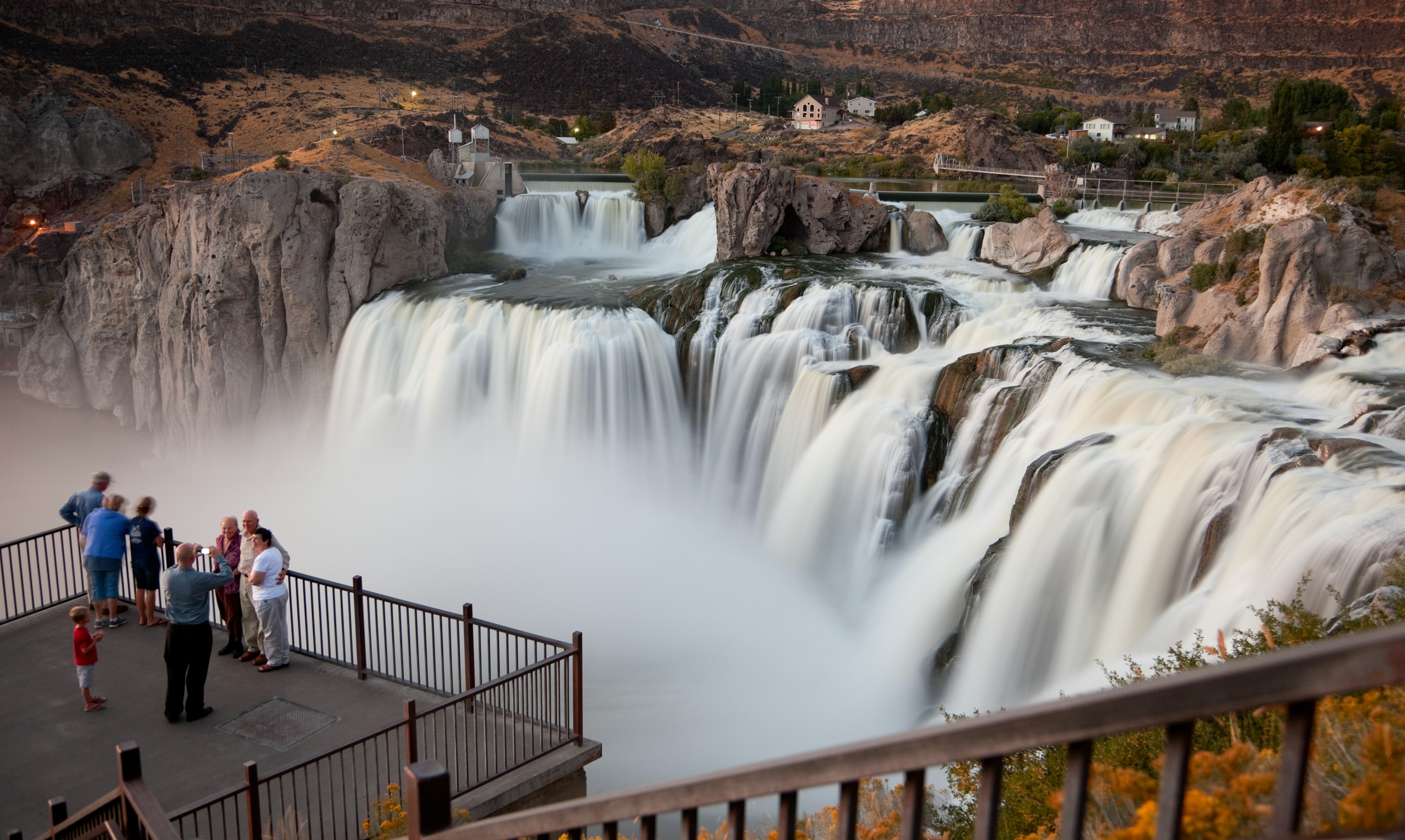 People pose for a photo on a viewing platform in front of a waterfall with several different cascades