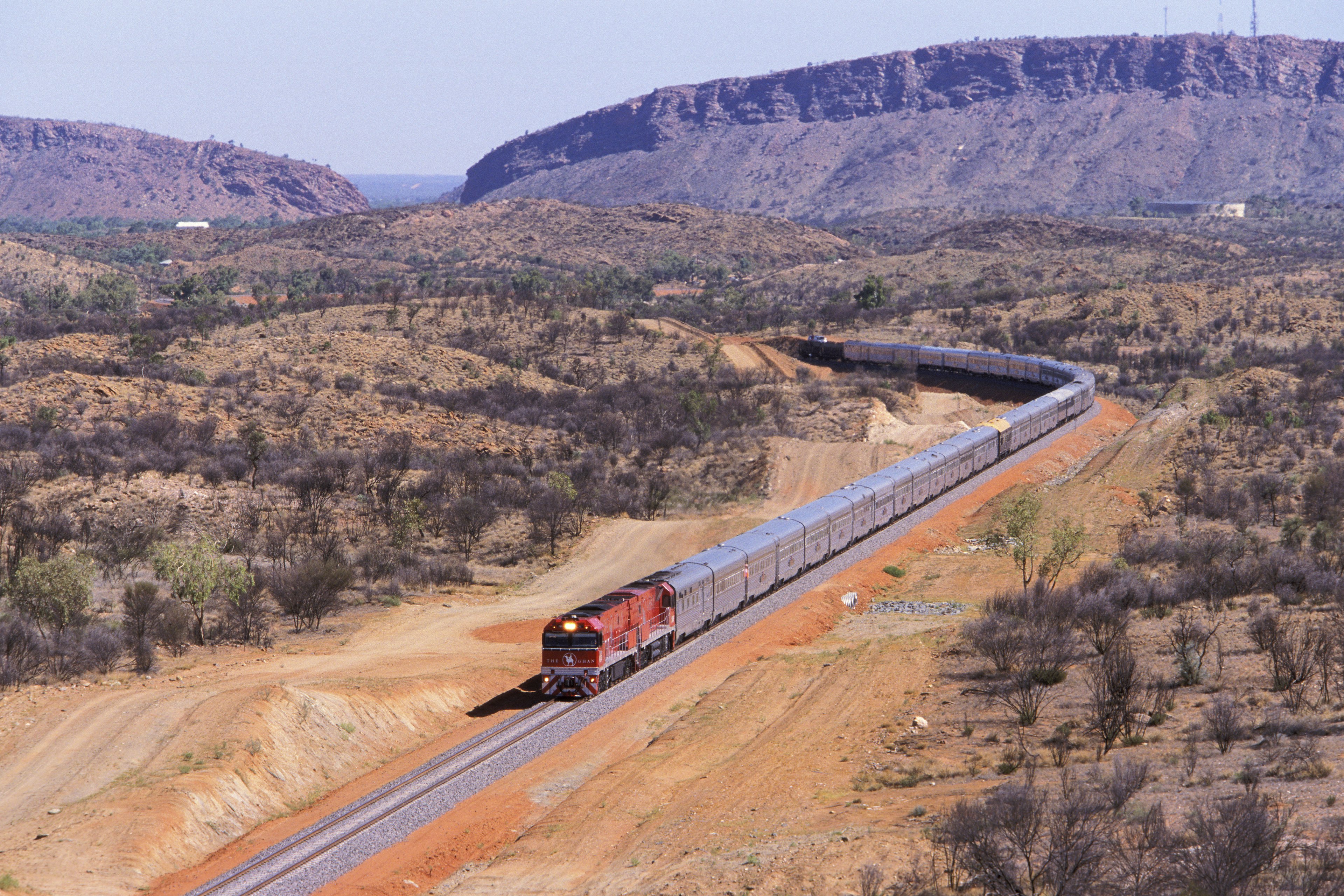 The Ghan train to Darwin, departing Alice Springs with the MacDonnell Ranges in the background