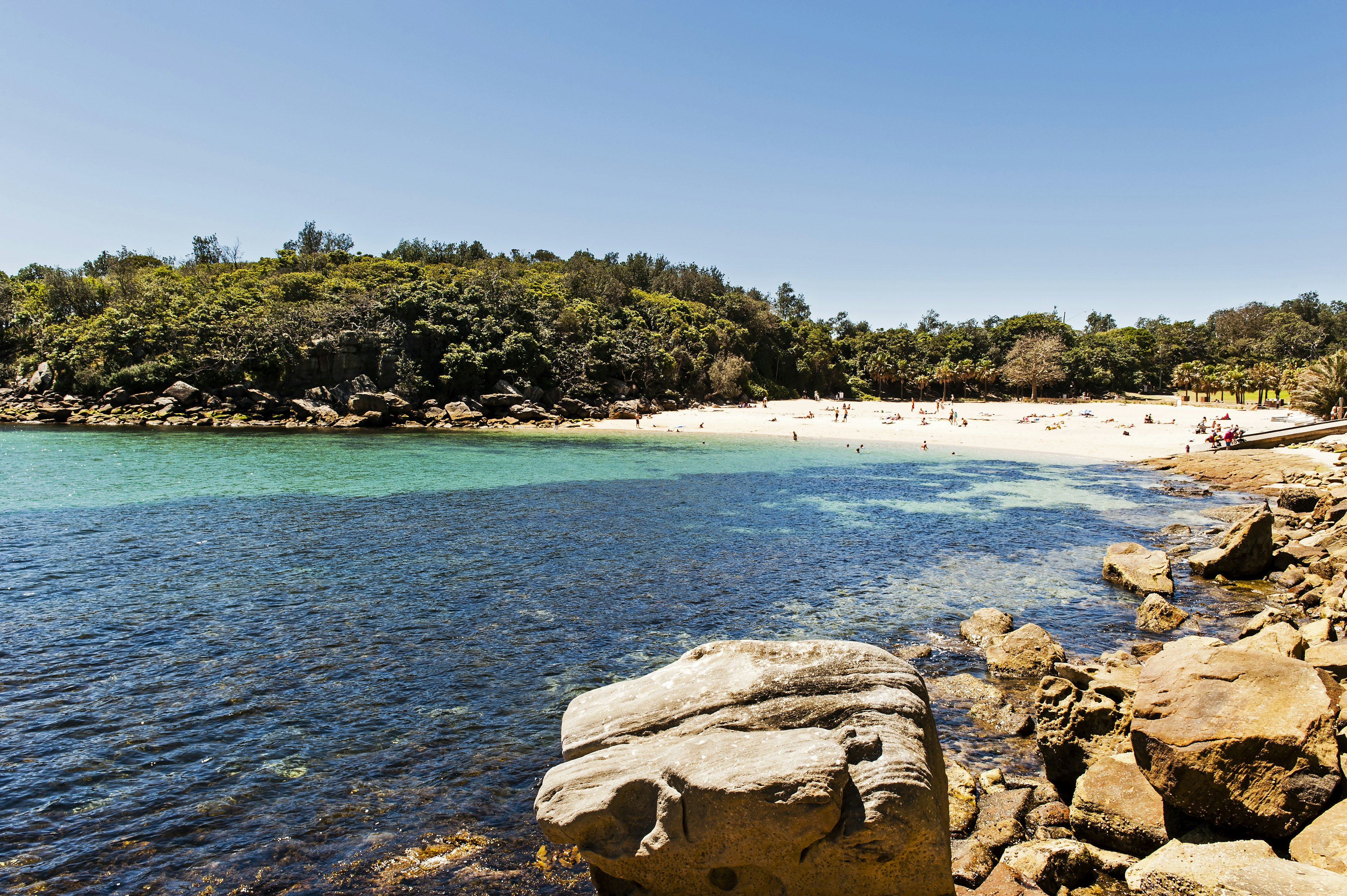 A sheltered bay with swimmers in its turquoise waters