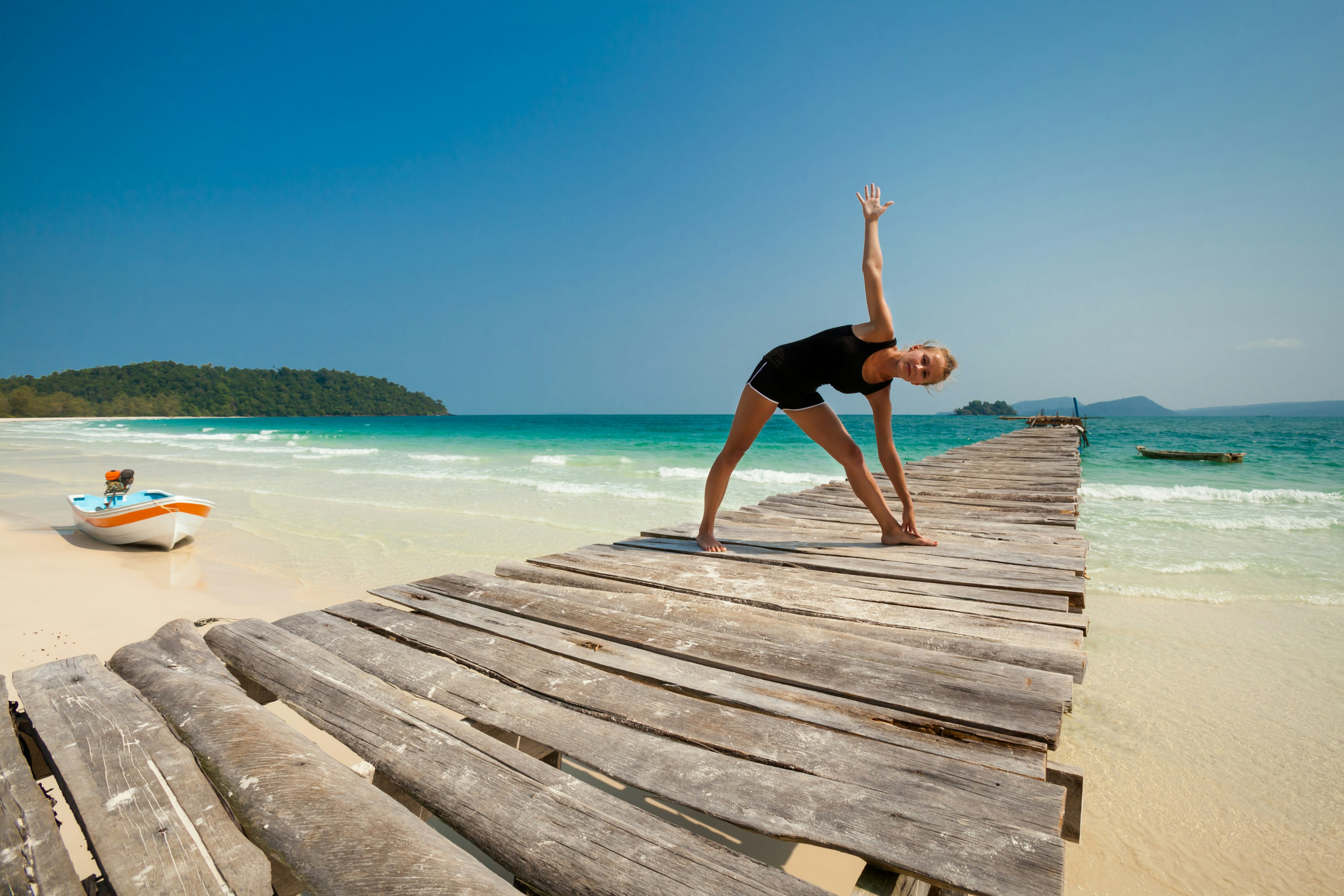 A woman enjoys a yoga session on a beach on Koh Rong, Cambodia